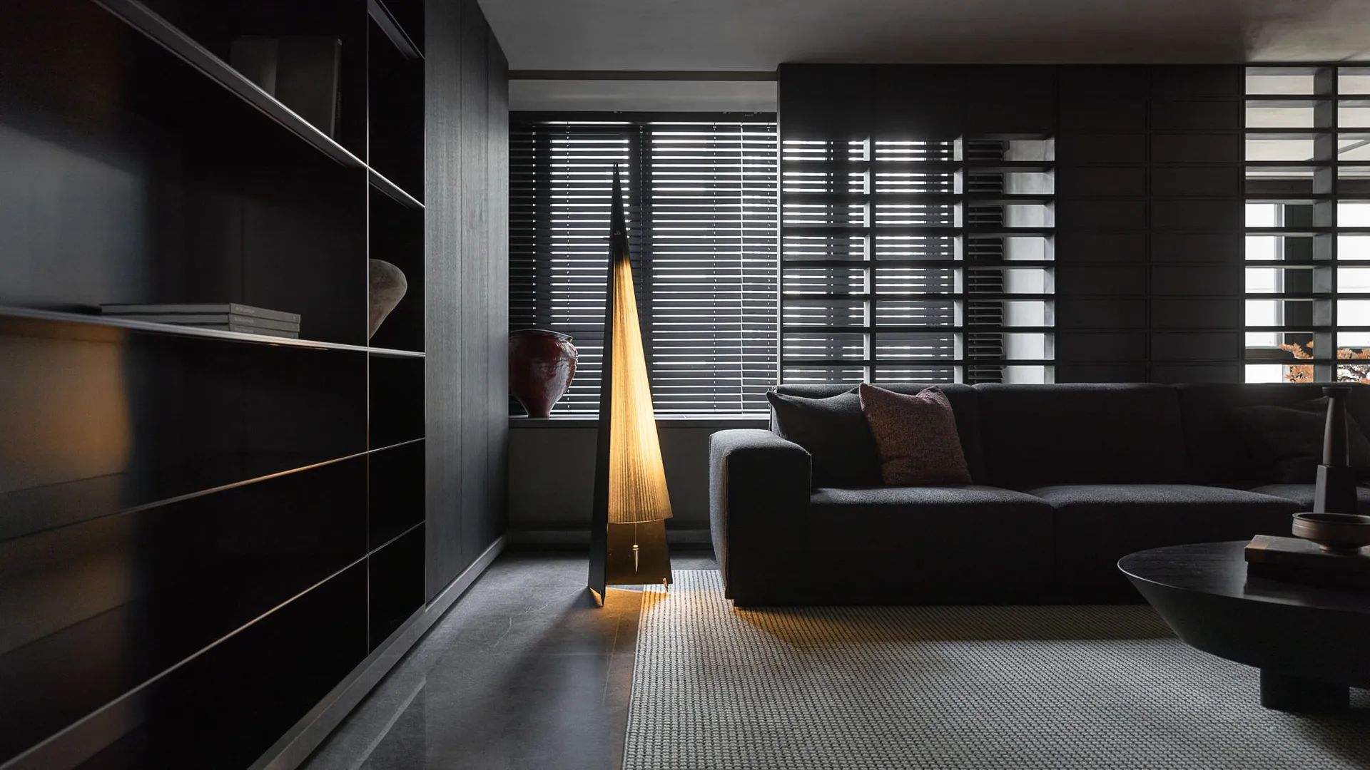 Modern living room with dark furniture and contemporary lighting.