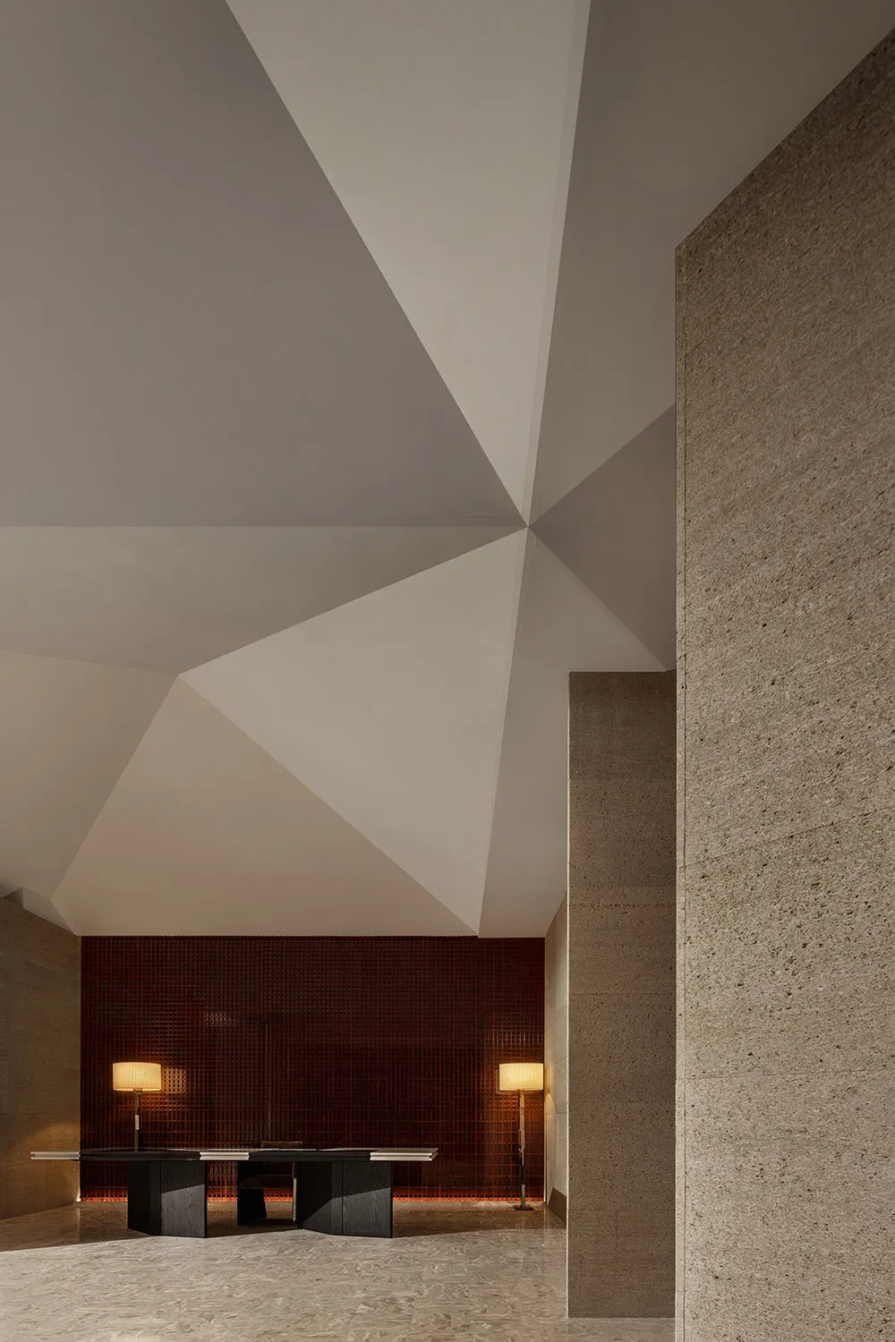 A modern office lobby featuring geometric ceiling designs, concrete walls, and sleek table setup.