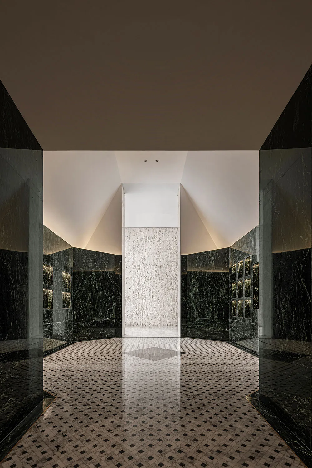 A modern marble hallway with geometric tiles and a white marble column in the center.
