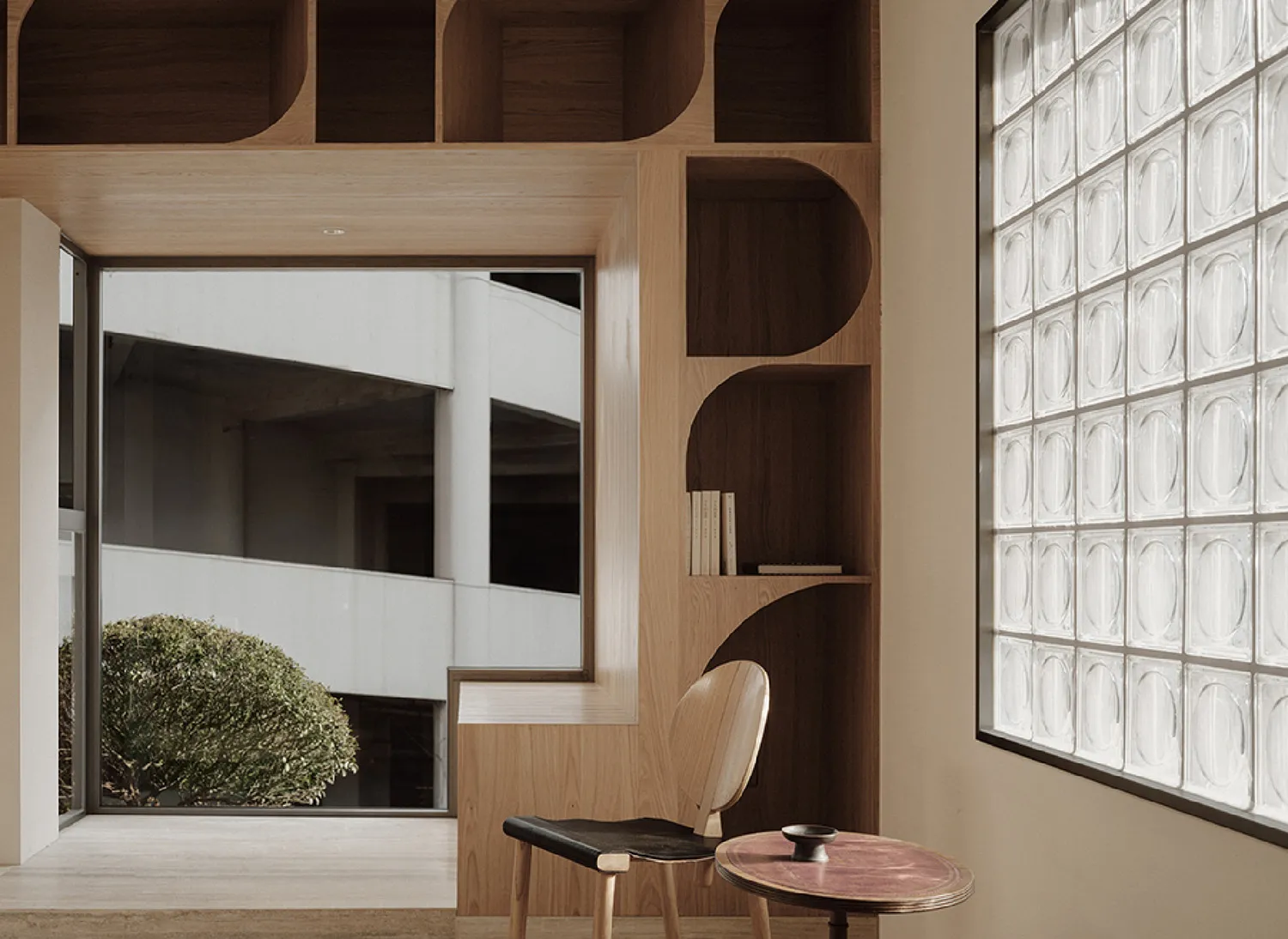 A minimalist interior design featuring wooden shelving and a glass block window.