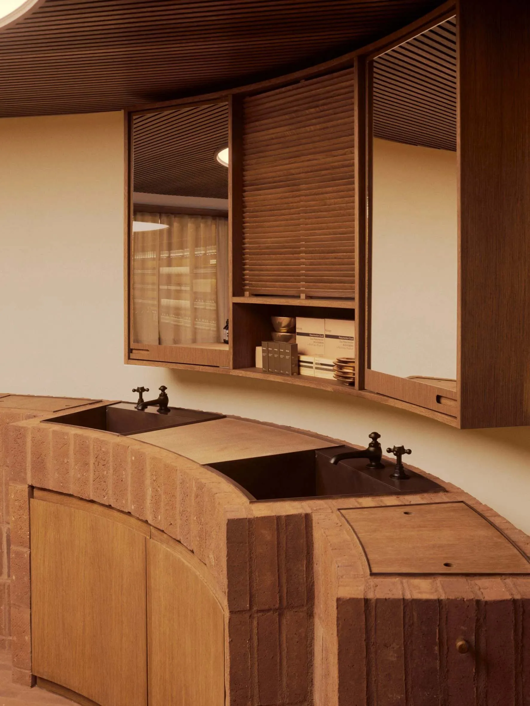 A modern kitchen with wooden cabinets and countertops, featuring a double sink and a shelf with storage items.