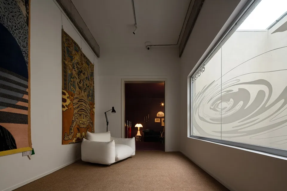 A modern living room featuring a white sofa and a large window with an abstract design.