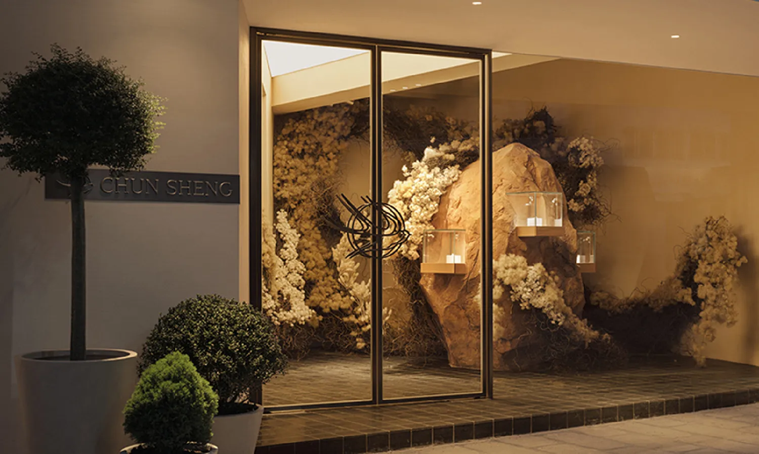 Modern retail storefront featuring glass facade with artificial plants and rock features