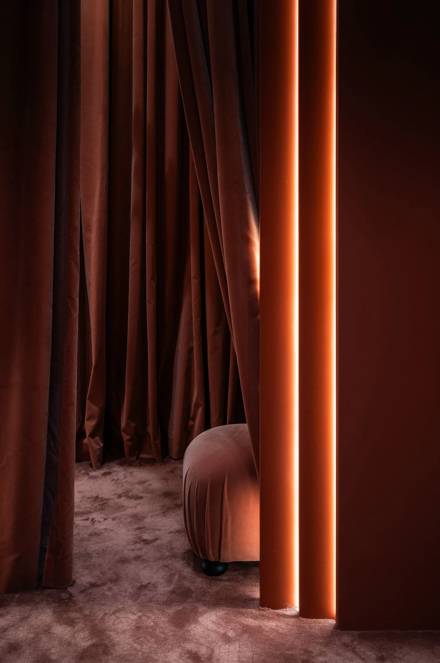 A modern interior design featuring dark velvet upholstery with orange neon lights.