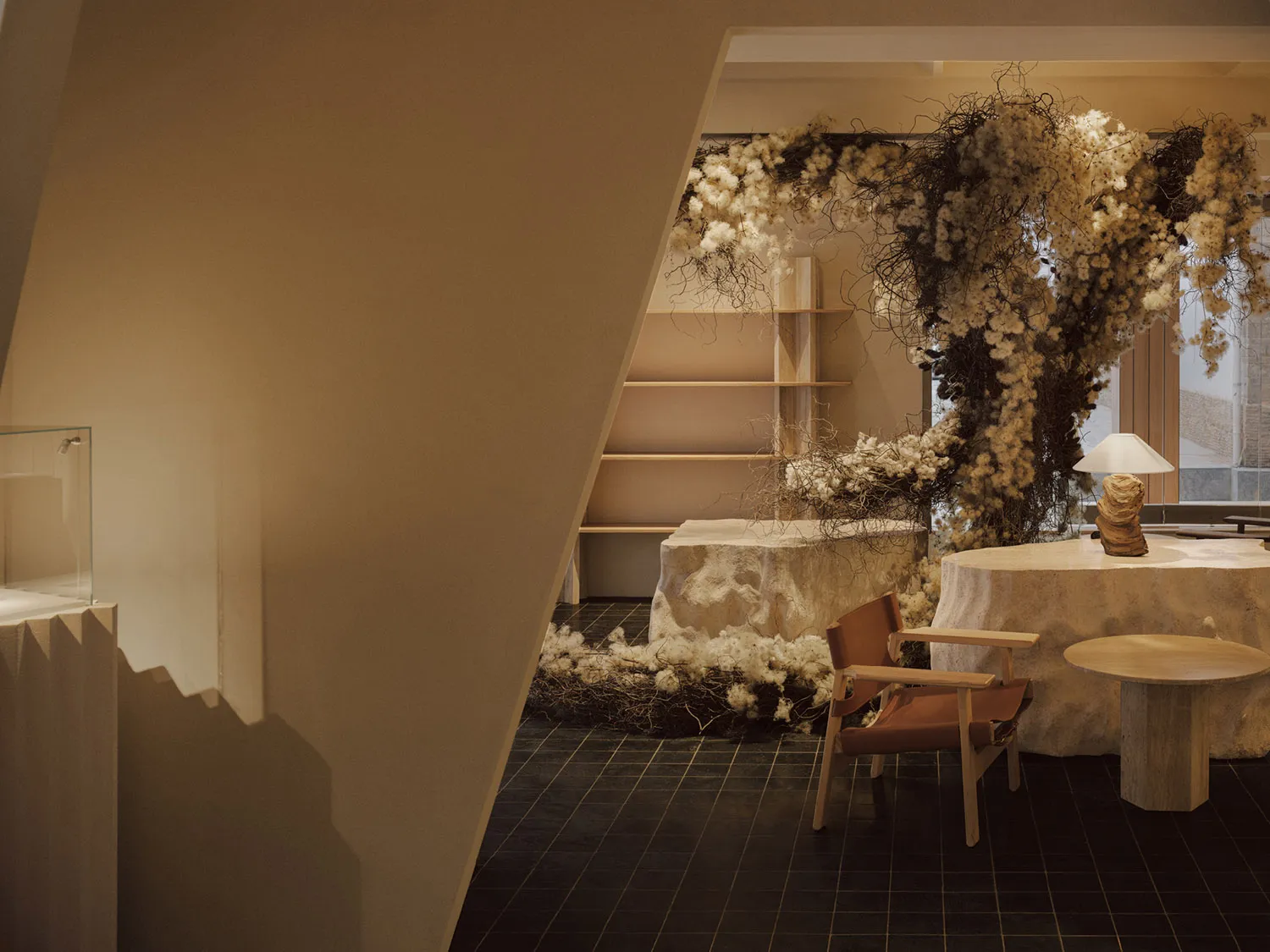A living room with modern interior design featuring a display area with cotton flowers, a wooden chair, and a round table.