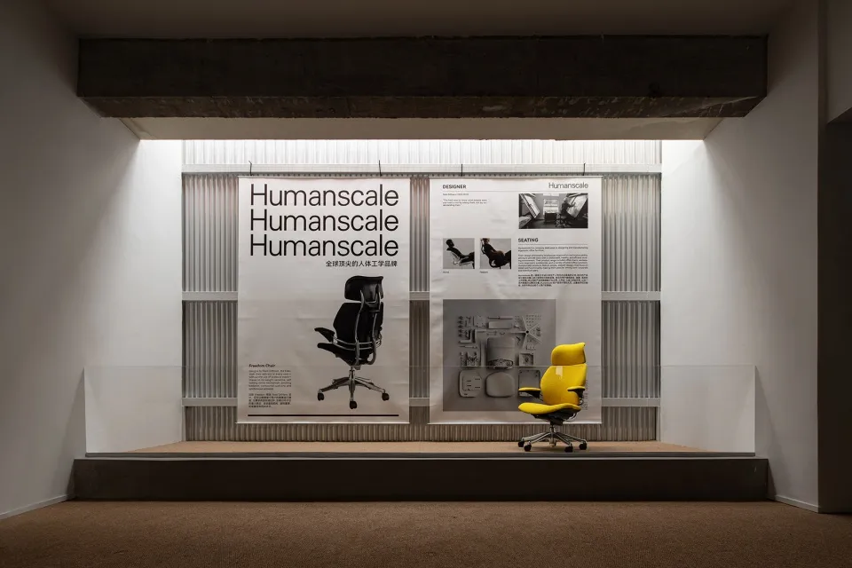 Humanscale 產品展示,黃色辦公椅置於階梯平台上,後方有資訊海報。