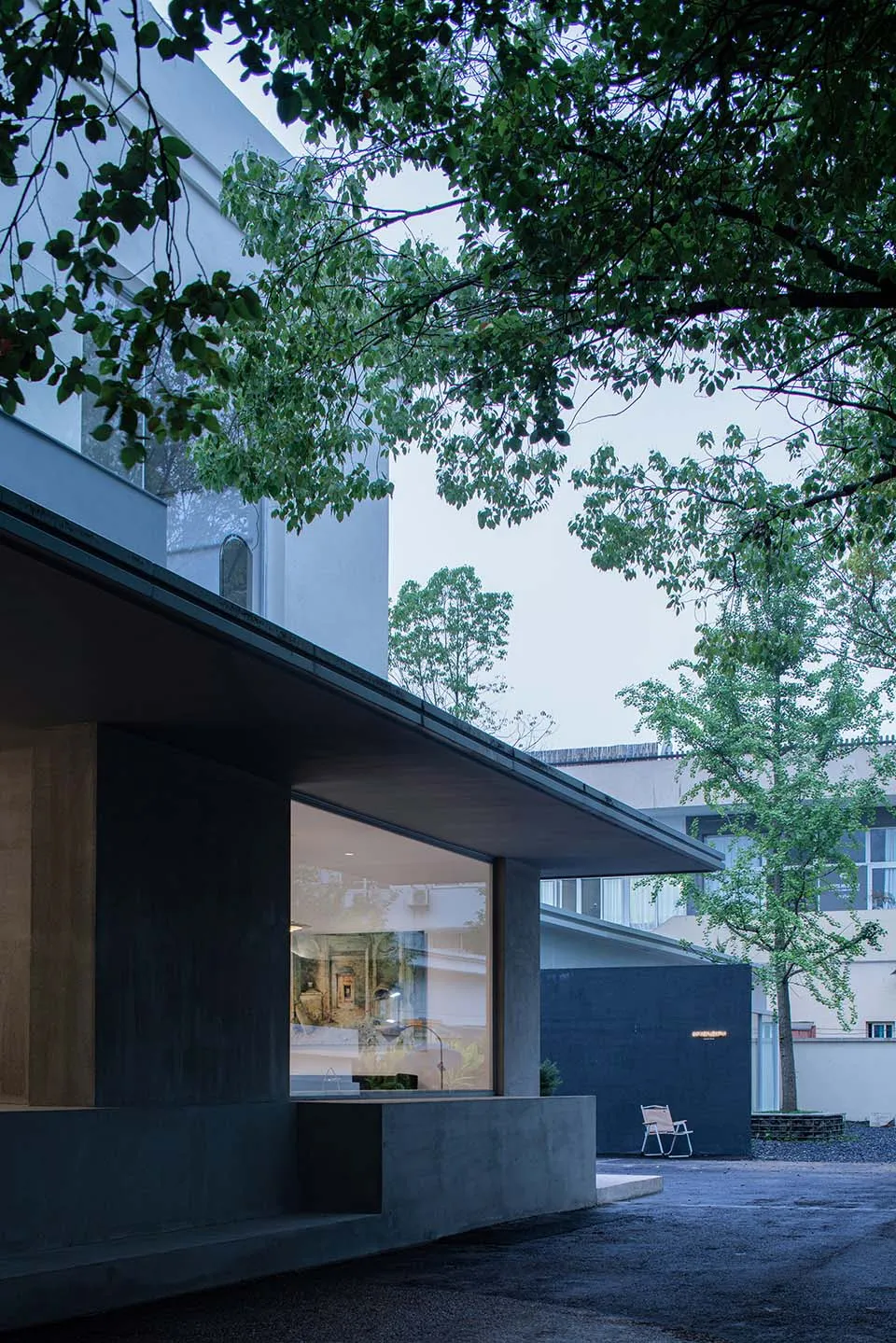 A modern outdoor space featuring a building with large glass windows and concrete walls.