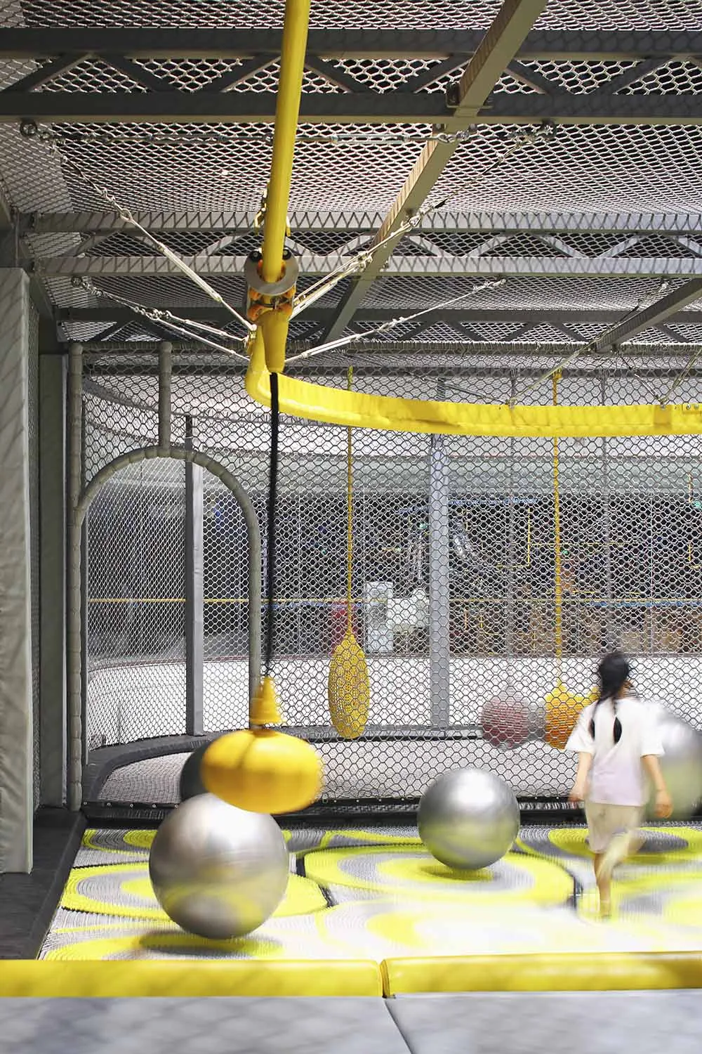 An industrial-style indoor playground with metal bars, foam spheres, and rubber flooring