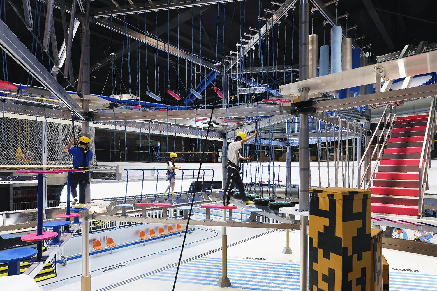 An industrial-styled playground with a metal rope course overhead