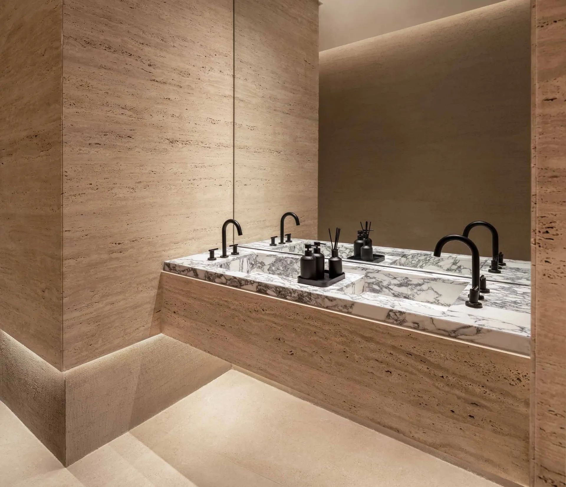 Modern bathroom with marble sinks and black faucets.