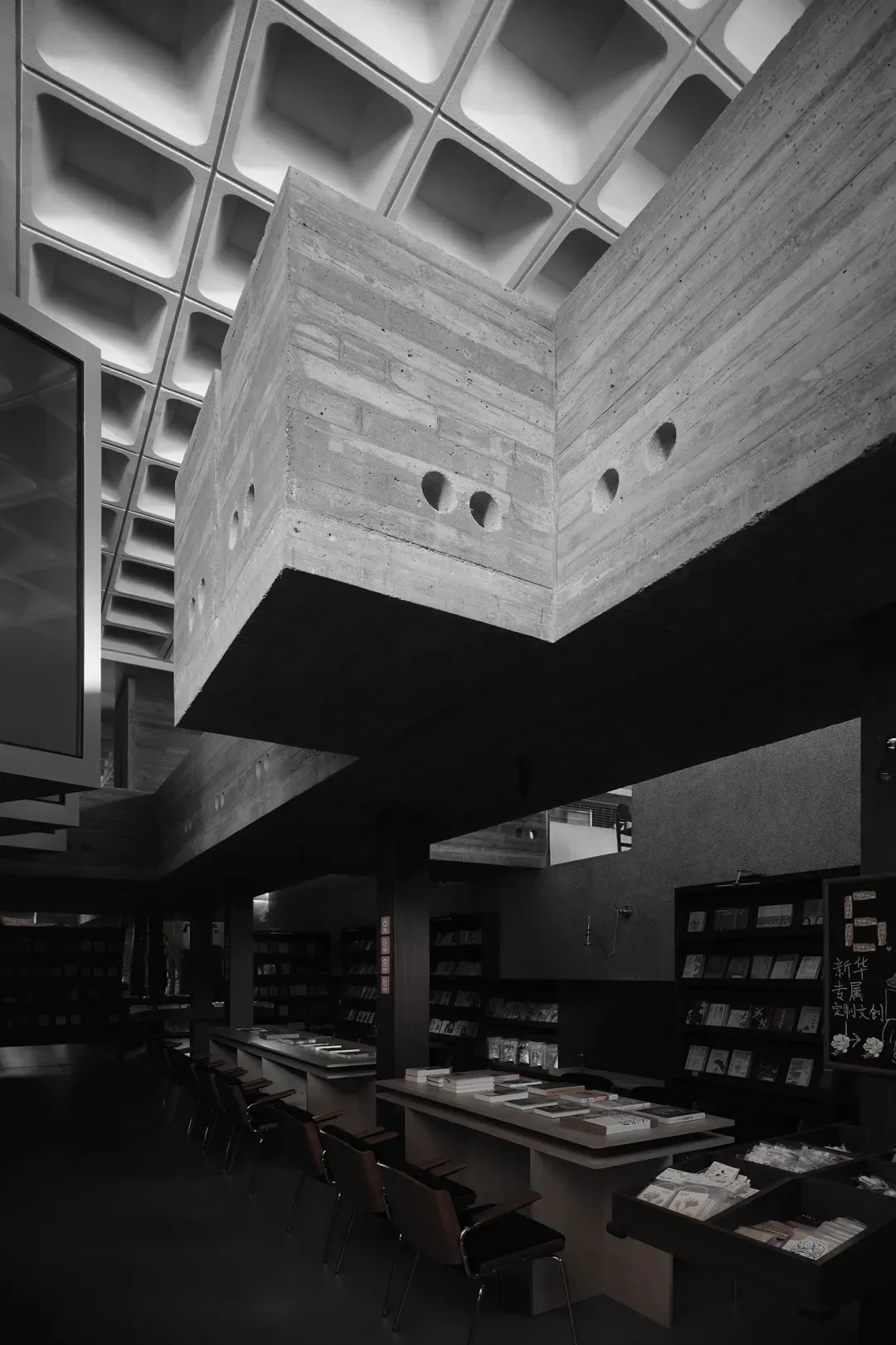 一座擁有混凝土牆面與透光天花板的現代圖書館，展現裸露混凝土樑與極簡設計。
