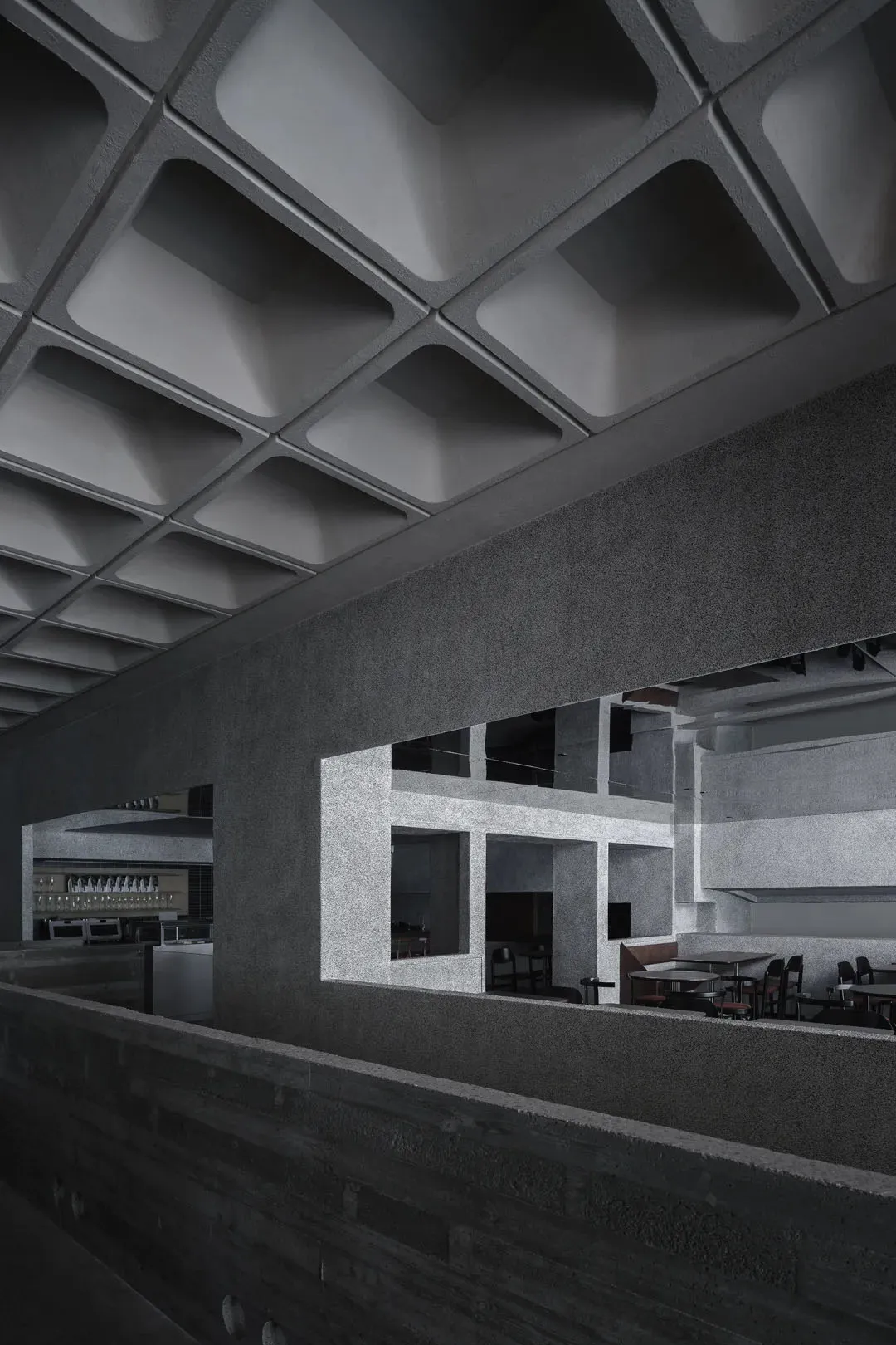 A minimalist restaurant interior with a concrete ceiling and metal walls.
