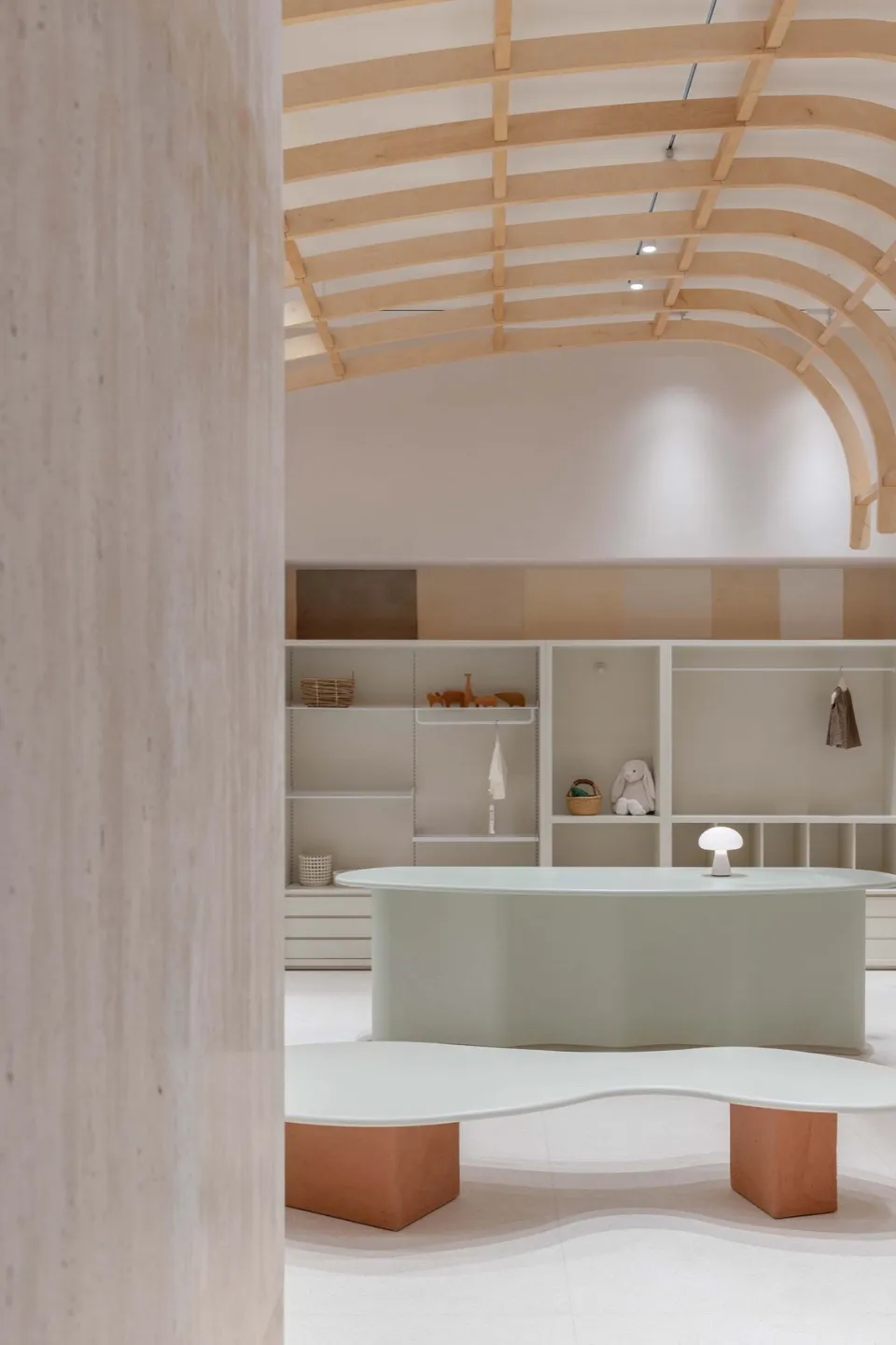 A modern showroom interior featuring a curved wooden ceiling and sleek, minimalist furniture.