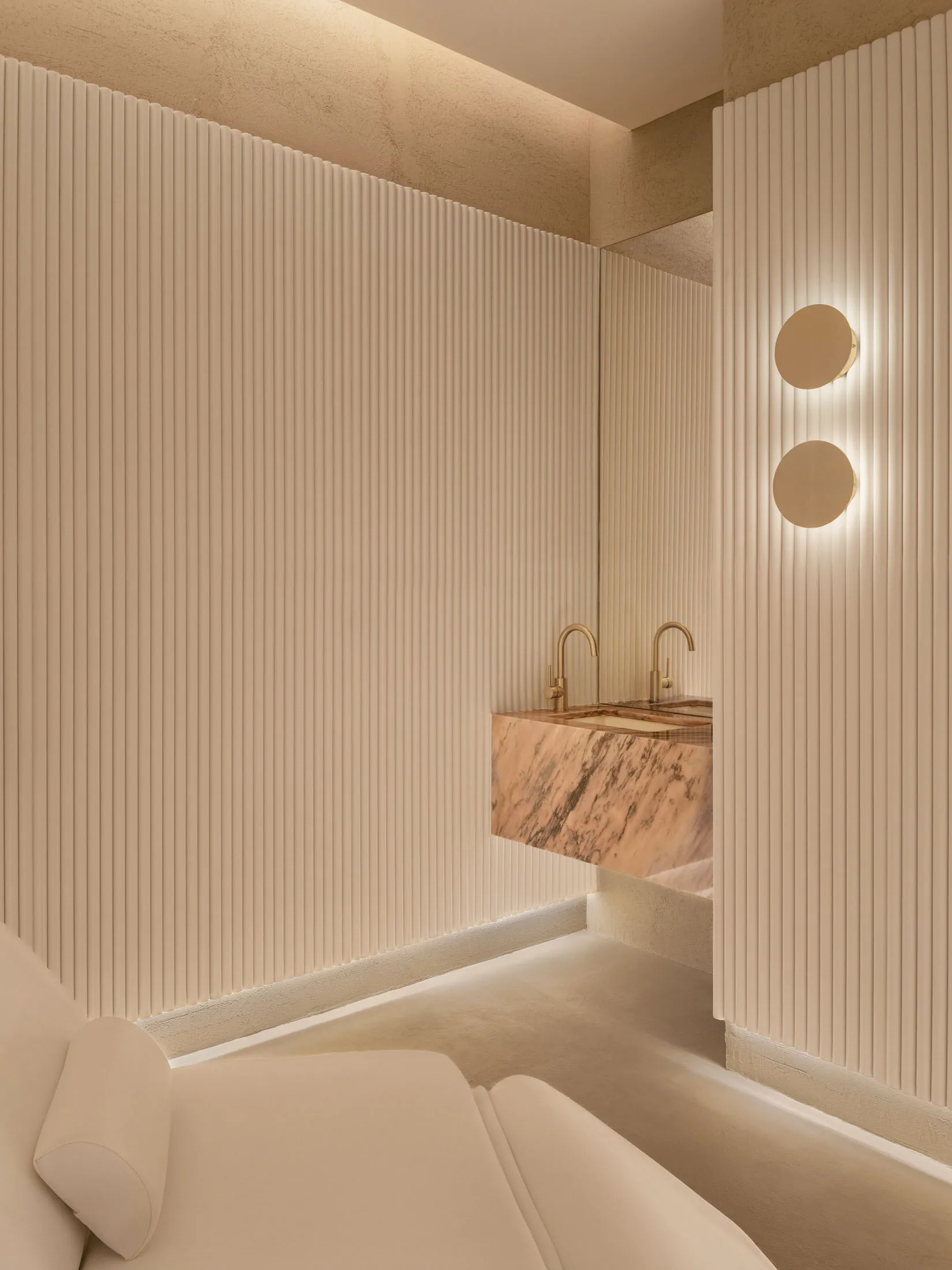 Modern bathroom featuring a marble sink vanity and concrete textured walls with soft lighting.