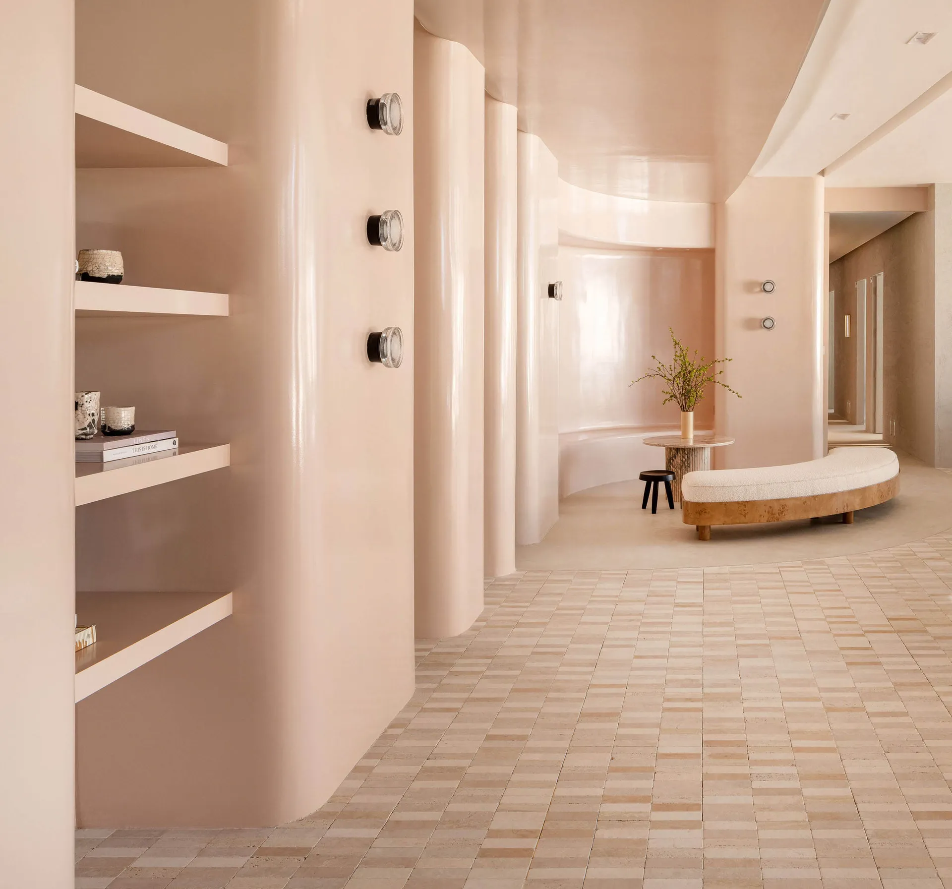 A modern interior space featuring a curved wall, shelves, and a curved bench with a plant, all set against a tile flooring ba