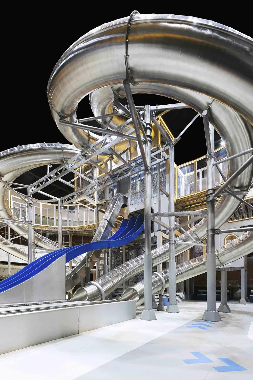 Metallic, industrial-style waterpark slide with blue water tubes and steel structure