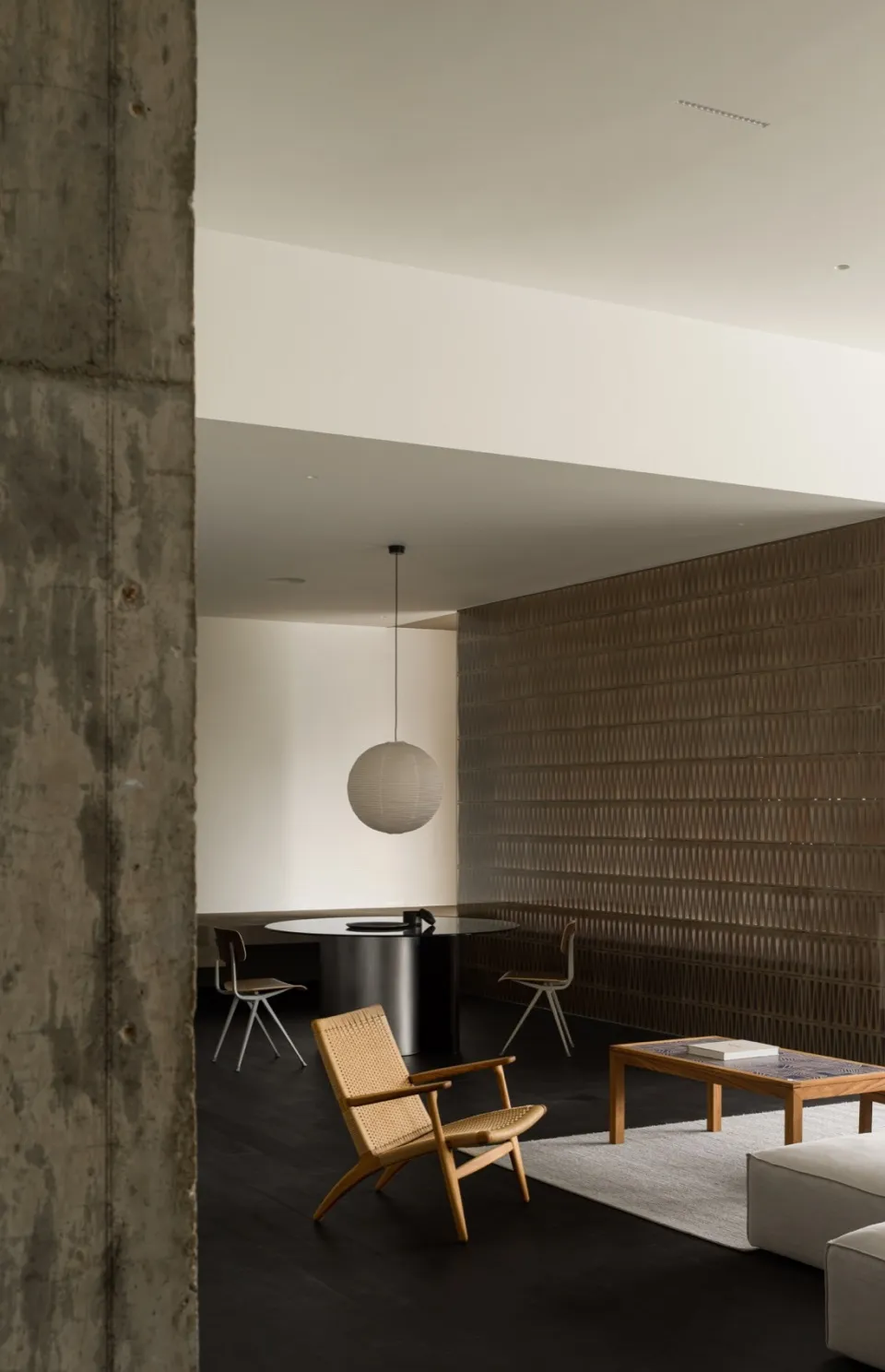 A minimalist living room featuring a concrete wall, wooden floor, and bamboo furniture.