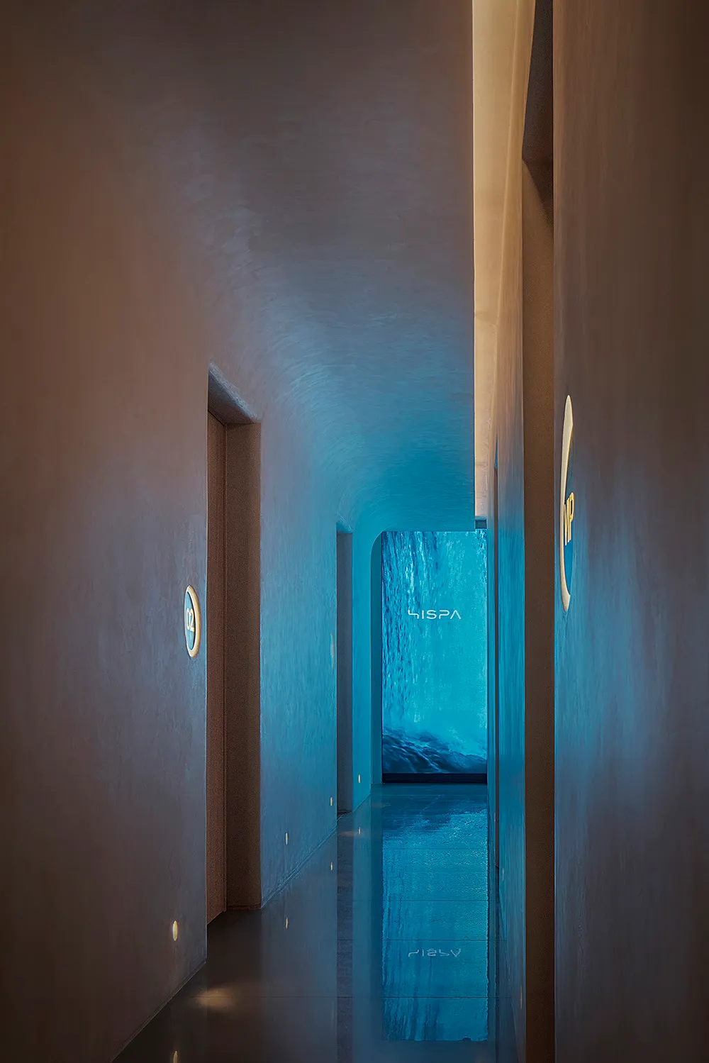 Modern hotel lobby with concrete walls and floors, featuring a waterfall in the background.