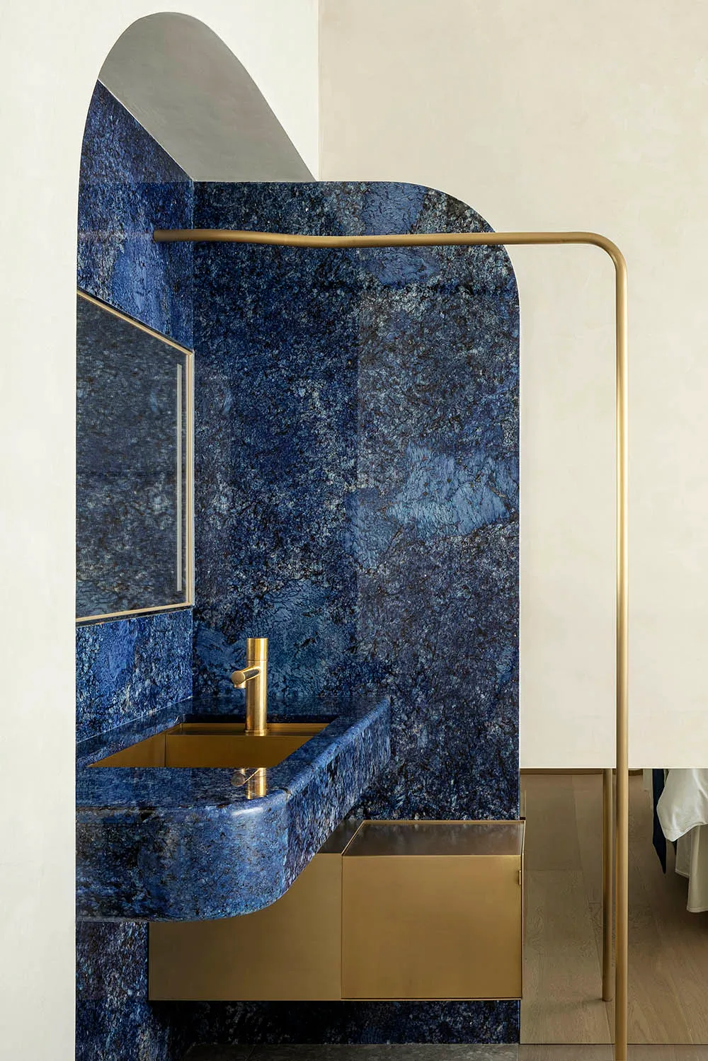 A modern bathroom with blue granite walls and minimalist brass hardware.