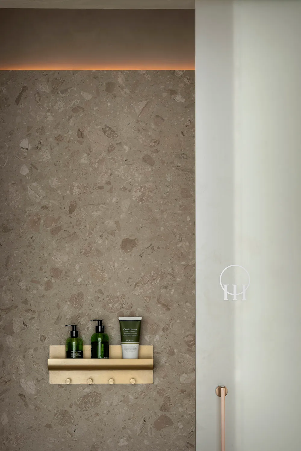 A minimalist bathroom showcases a concrete shelf with various toiletries.