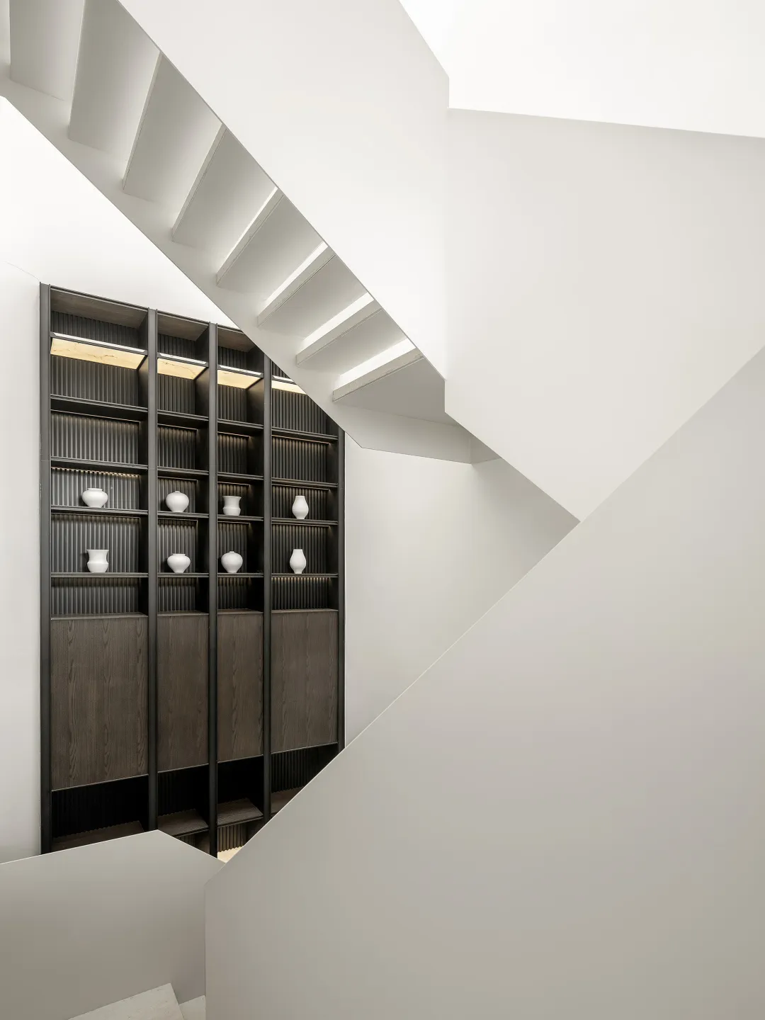 A modern staircase with white concrete steps and black wooden railings.