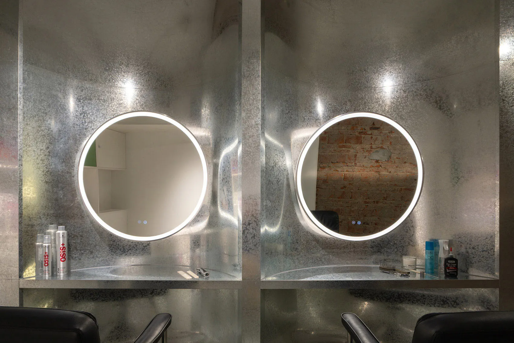 A modern salon interior with metallic glass walls and circular mirrors.