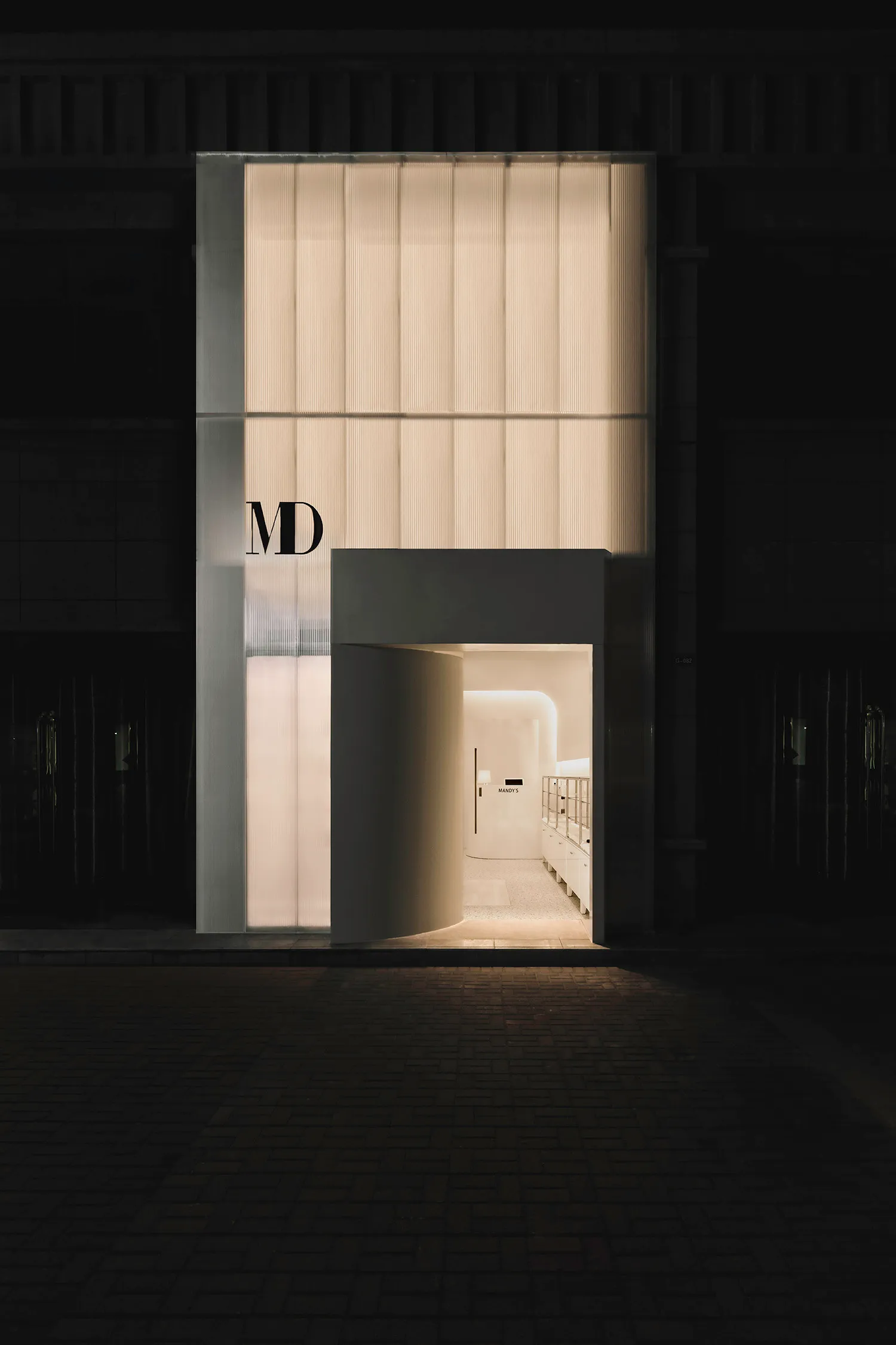 Modern retail storefront featuring framed glass panels at night.