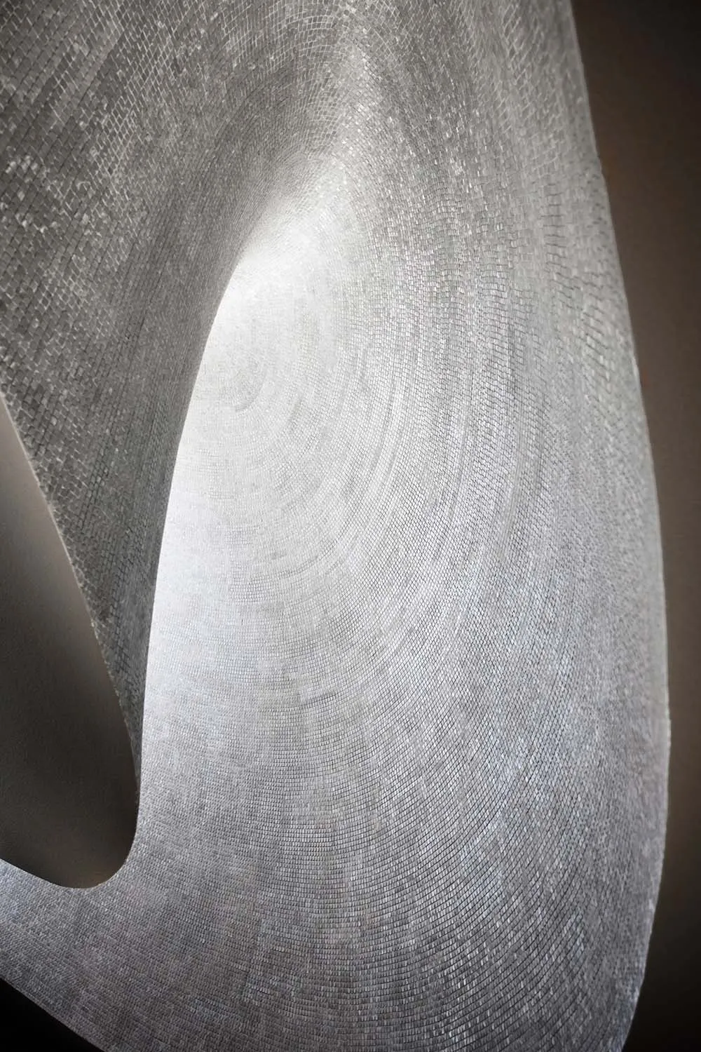 A close-up image of a textured, abstract metal sculpture created from mosaic tiles.