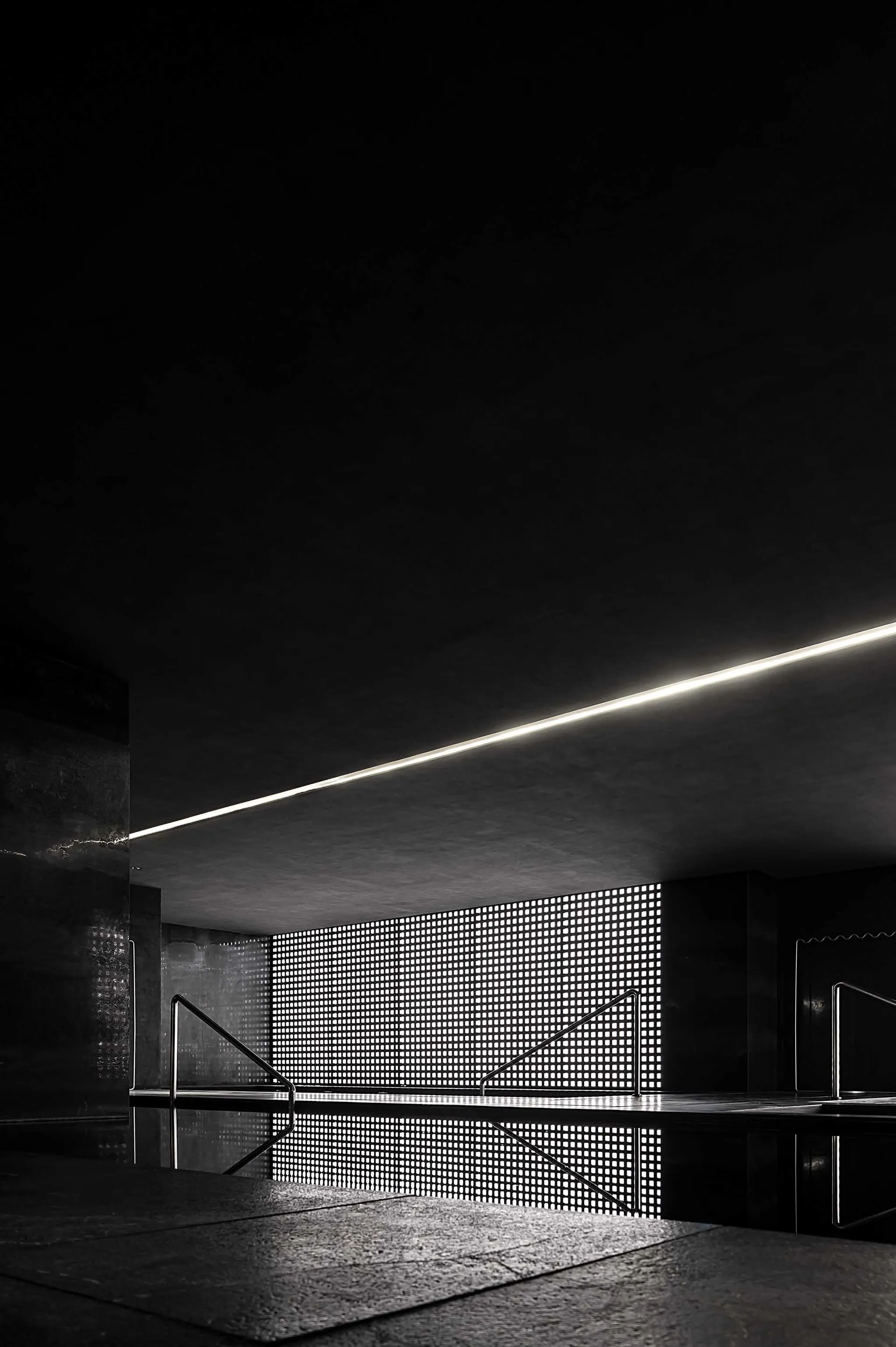 A modern indoor space with a minimalist design, featuring black and white color scheme and metallic, perforated materials.