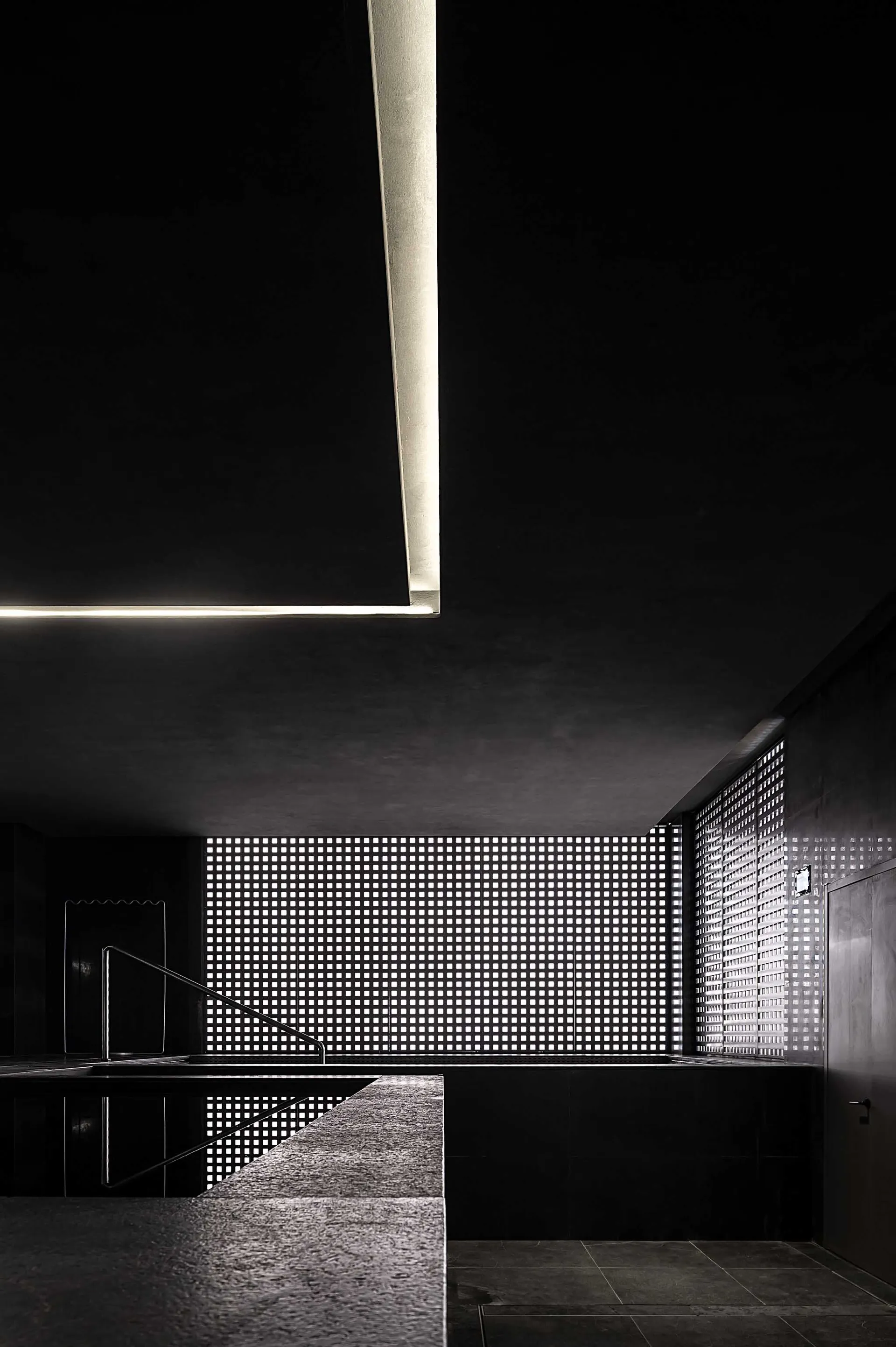 A modern interior featuring a black metal wall lattice, minimalist design, and geometric shapes.