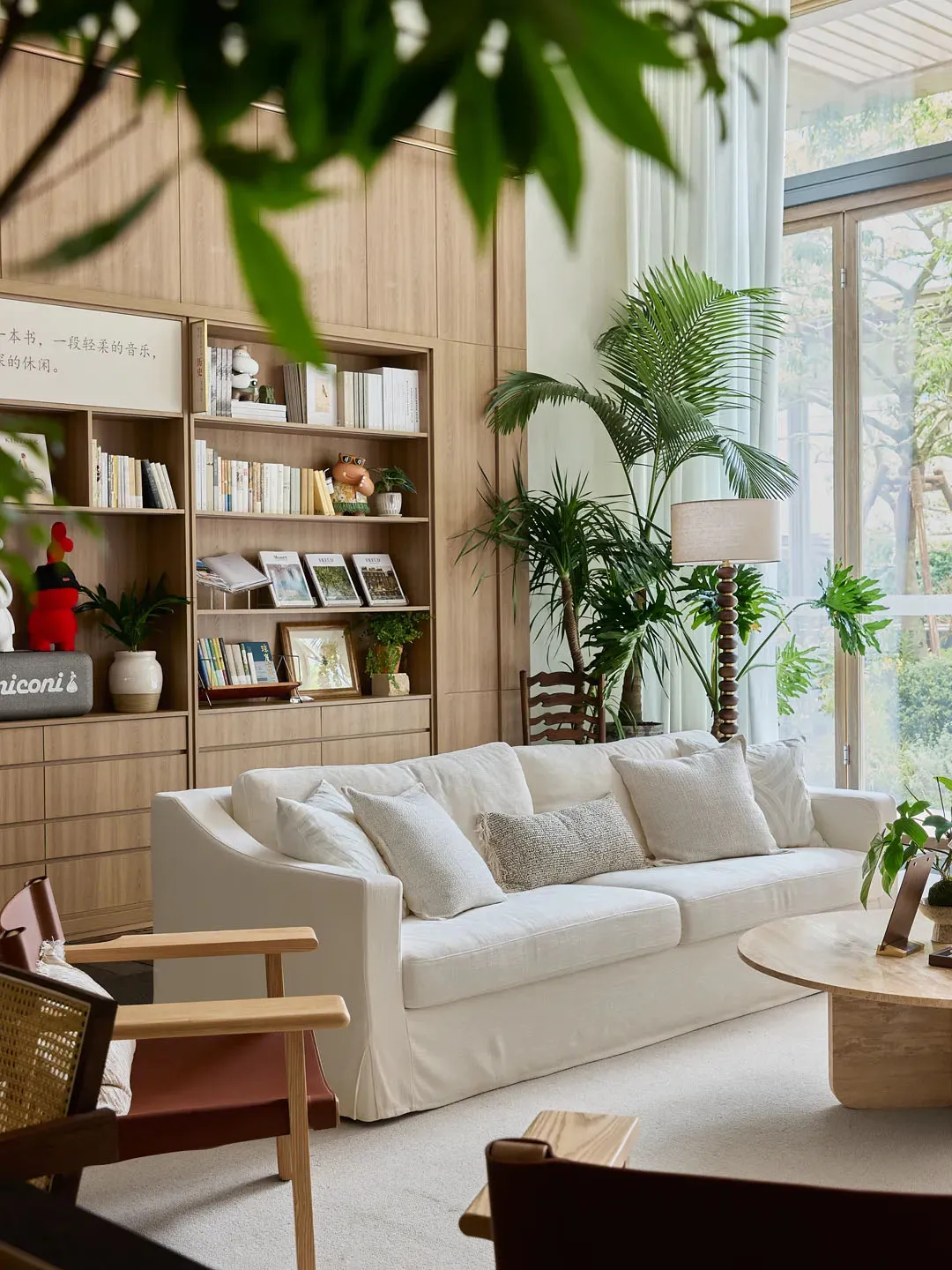 Modern living room featuring white furniture, wooden shelves, and potted plants