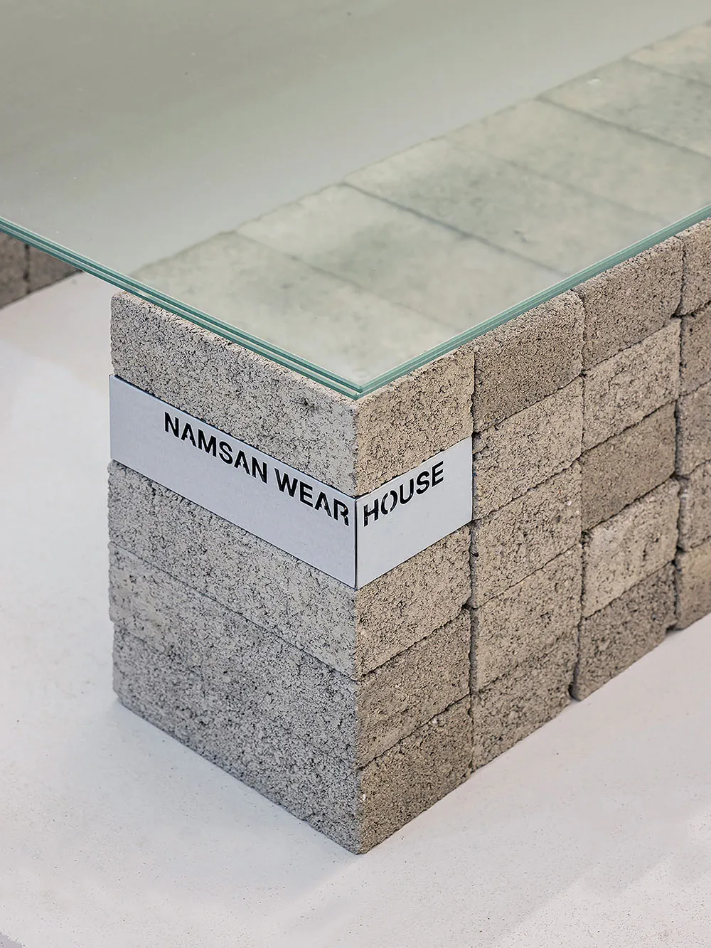 A minimalist desk with a glass top and a base made of stacked concrete blocks.