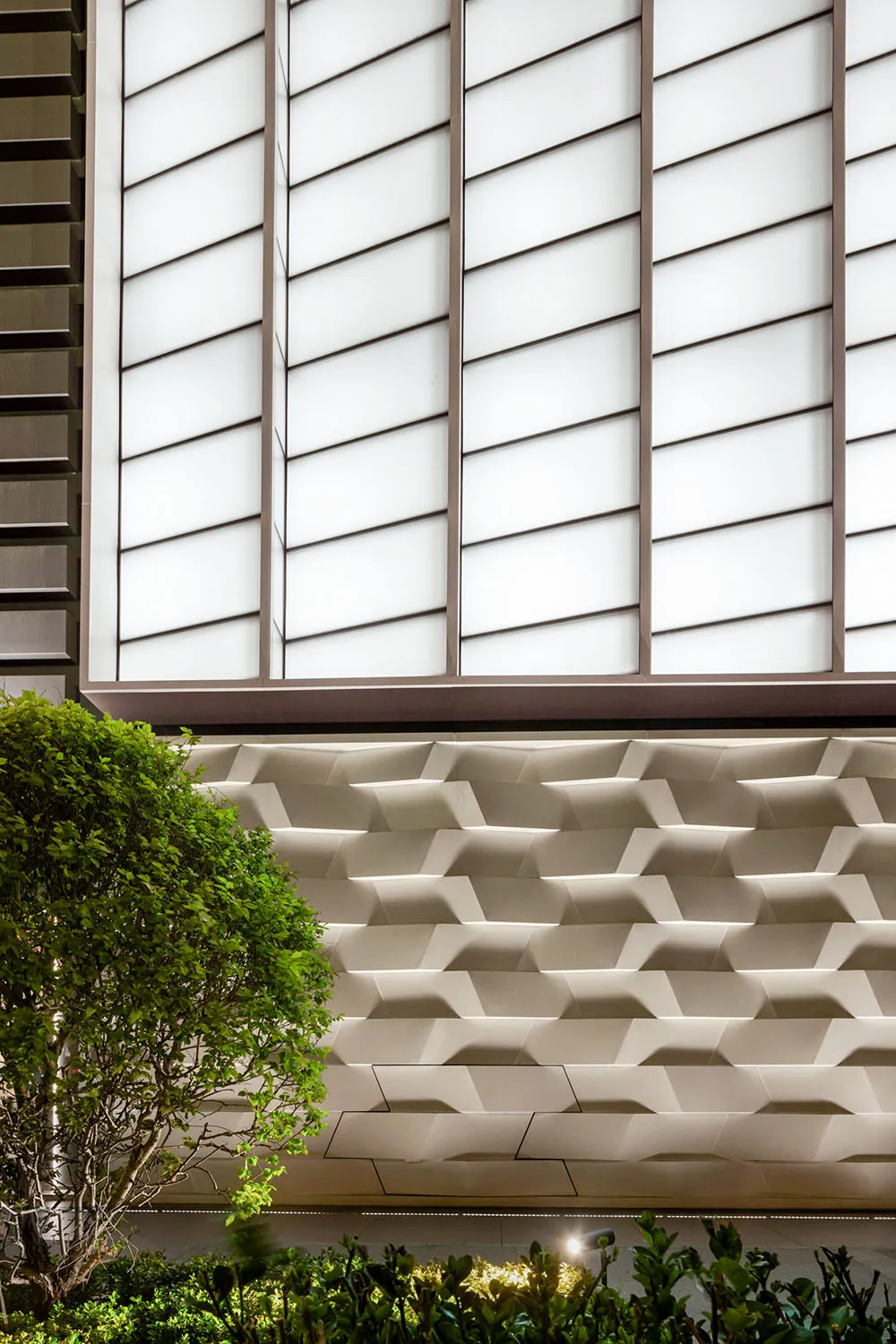 Modern architectural design featuring a textured concrete exterior with large glass windows.