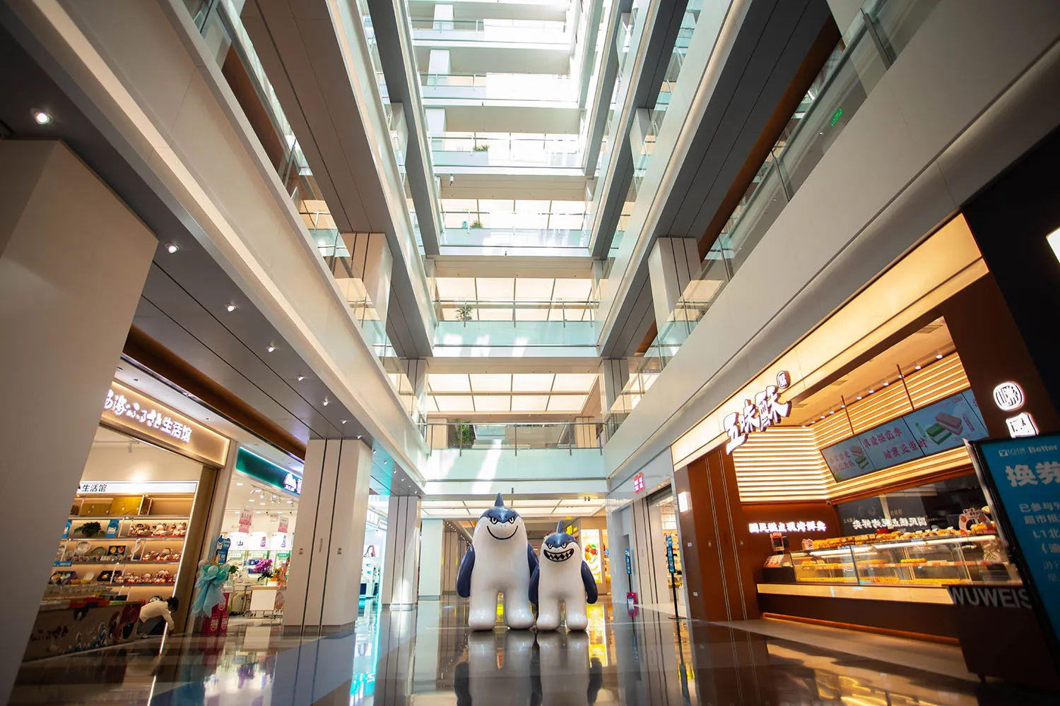 A modern mall interior featuring glass, metal, and concrete elements.