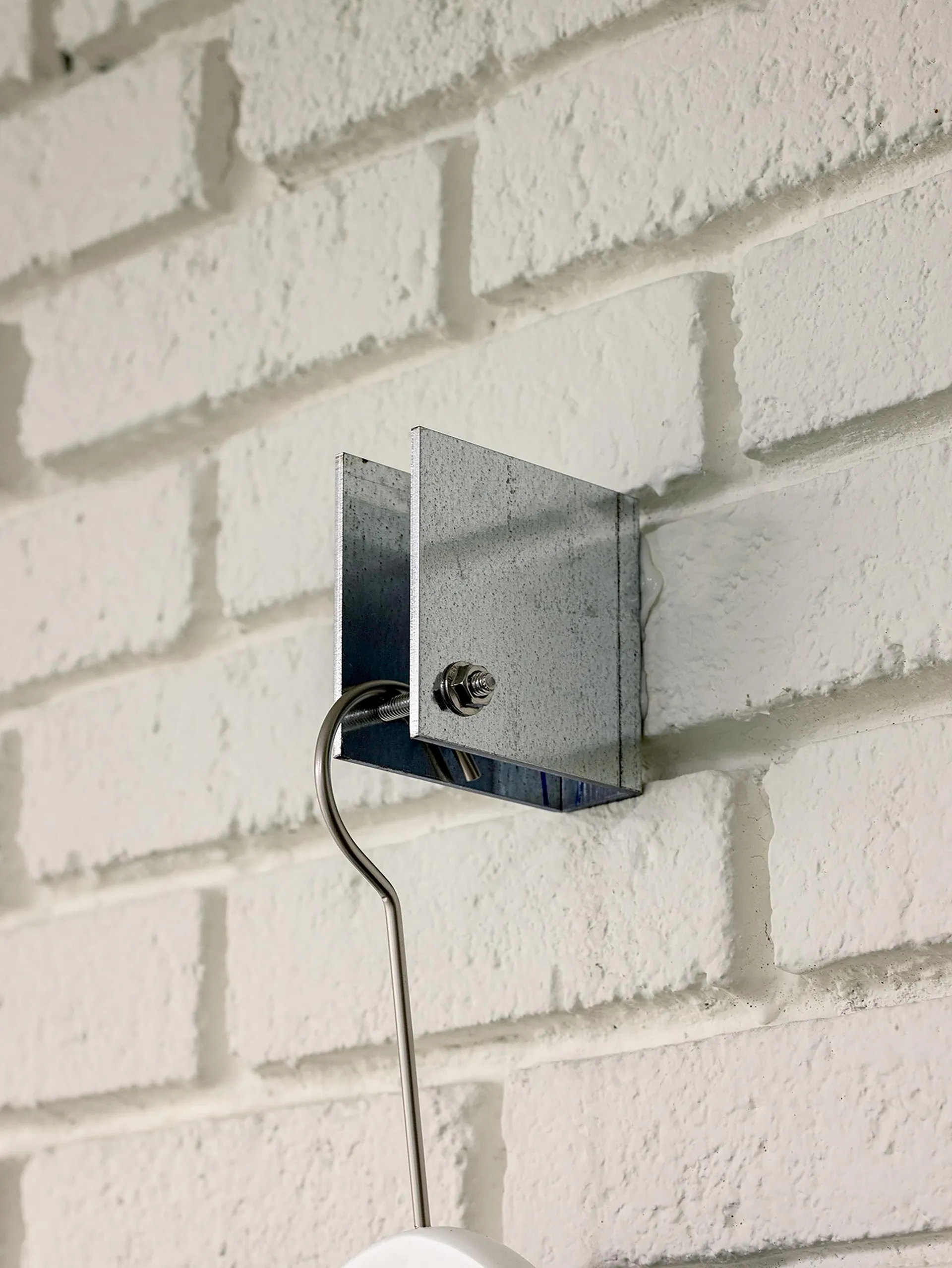 Metal lighting fixture mounted on a white brick wall