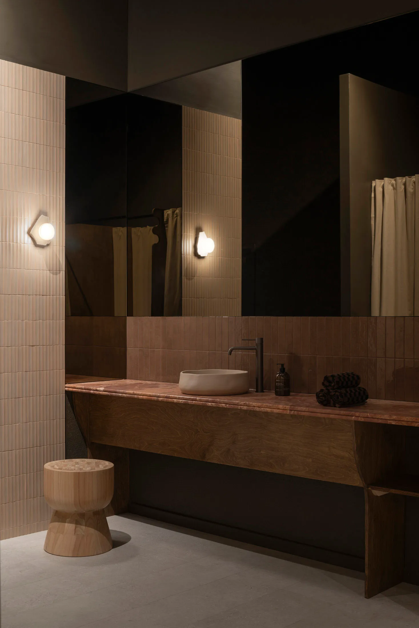 A modern bathroom featuring a ceramic sink, wooden vanity, and glass tile walls.