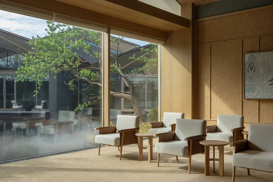 A modern lobby with paper wall tiles, a hanging painting, and wooden furniture.