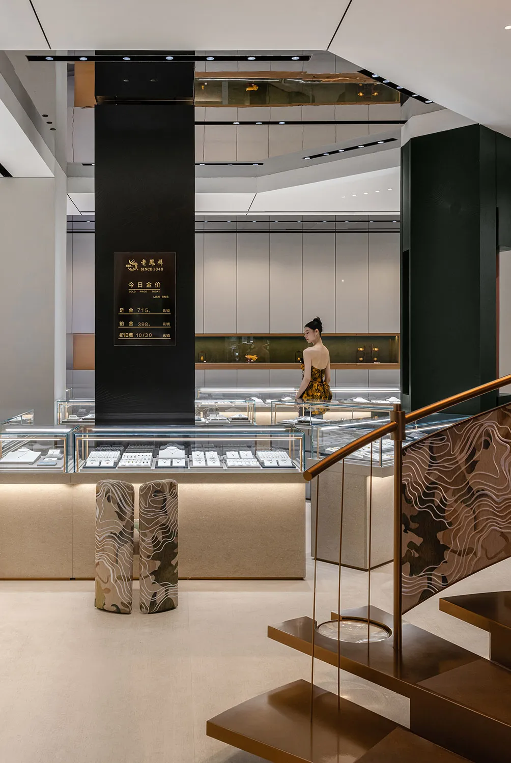 Interior of a modern jewelry store with glass display cases, wooden stair railings, and a metal pillar.