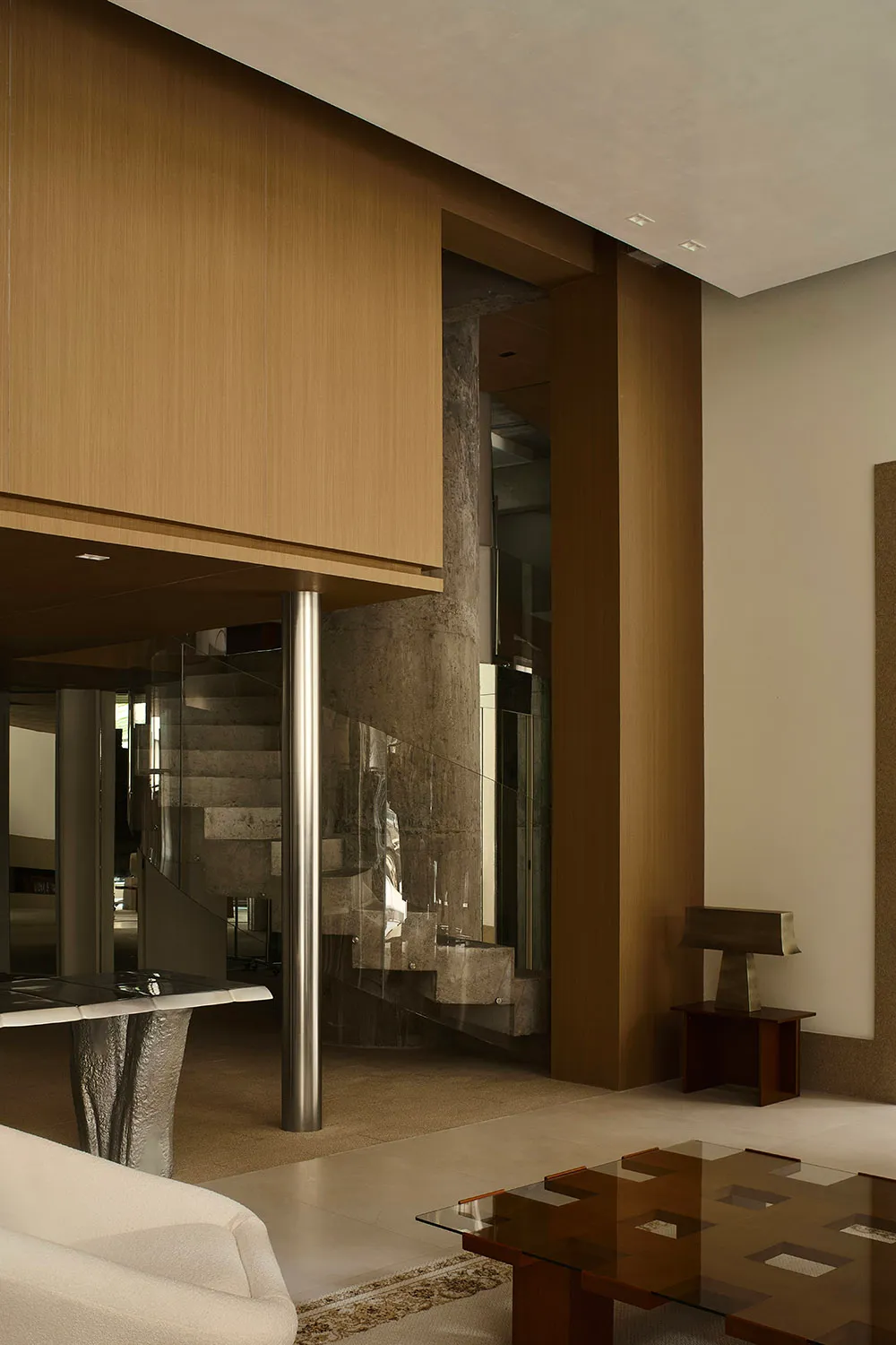Interior design featuring modern living room elements including wood-paneled walls, concrete columns, and glass panels