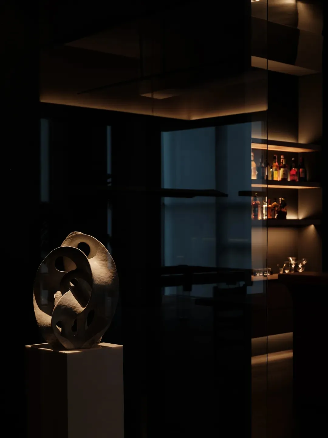 Modern bar interior with glass shelving and illuminated bottles.
