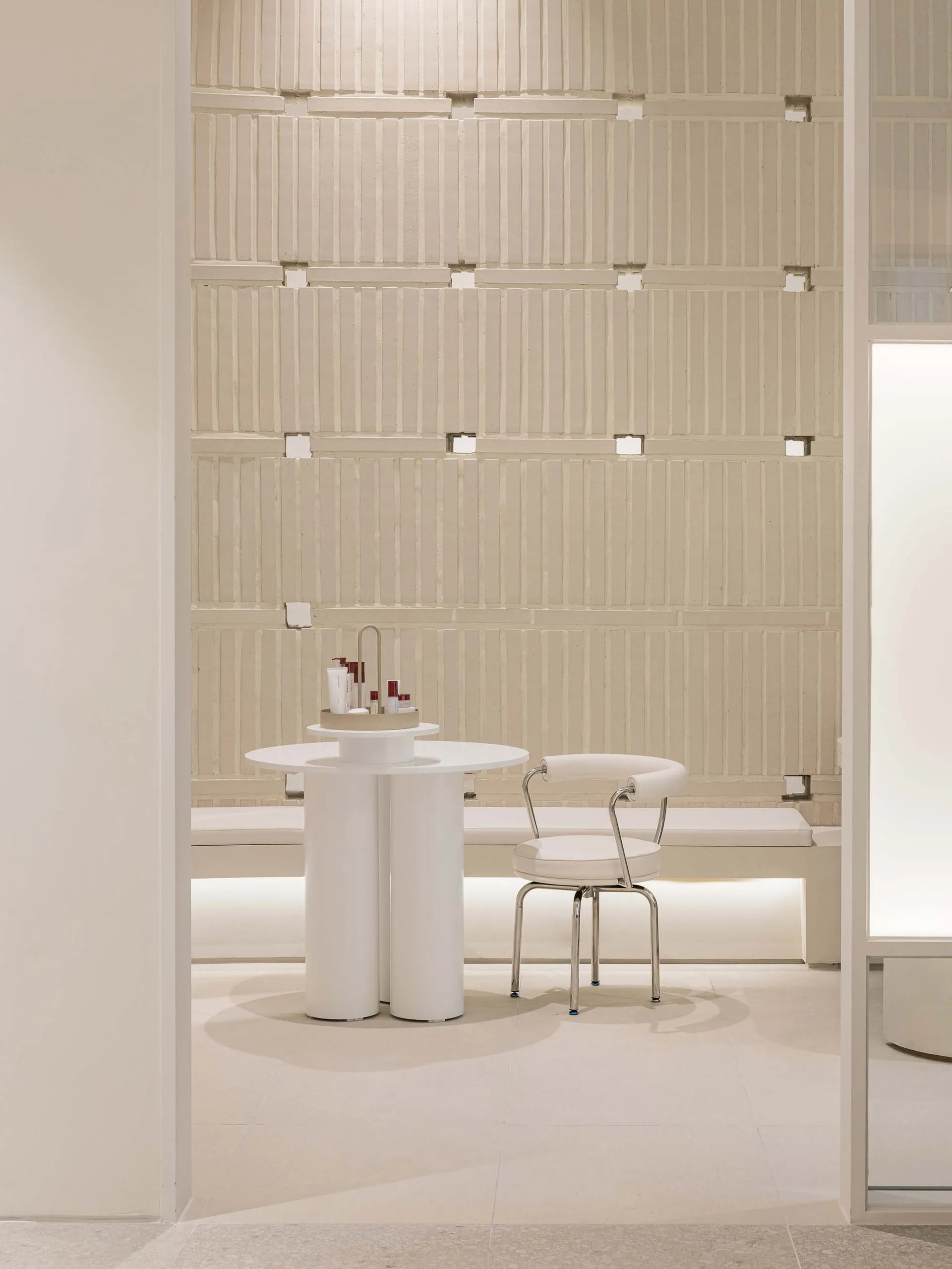 A minimalist interior space with a concrete wall and white furniture.