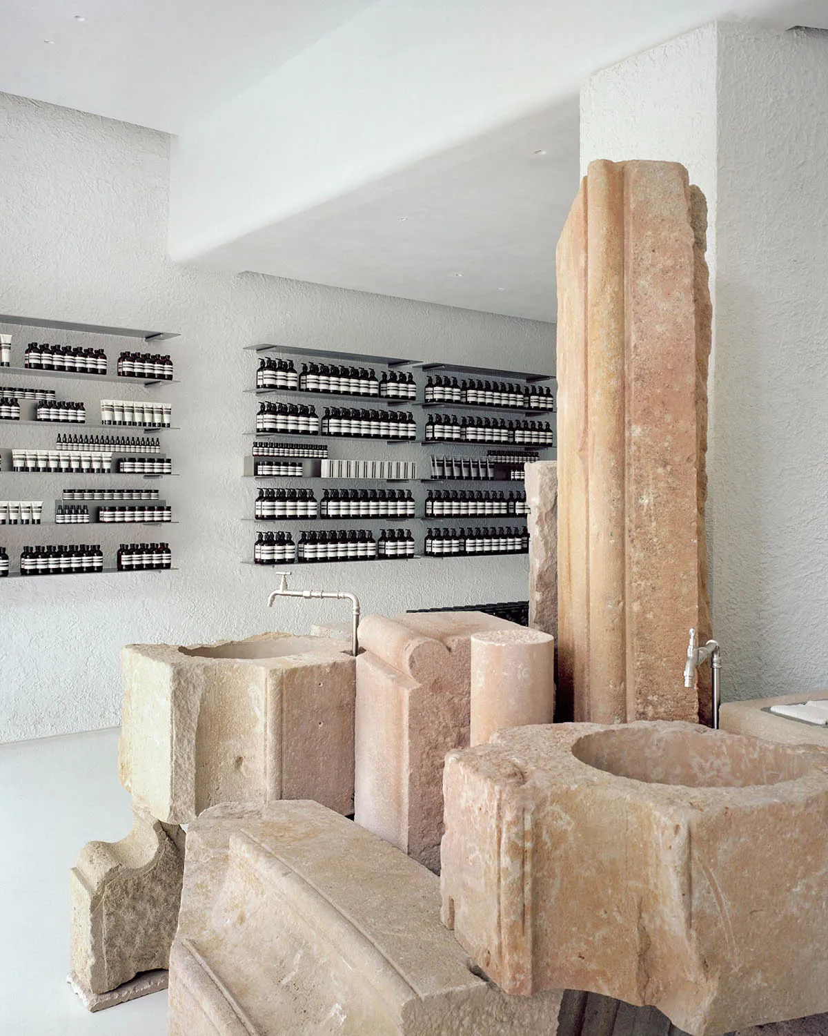 Minimalist retail storefront showcasing stone shelves and products on white shelves