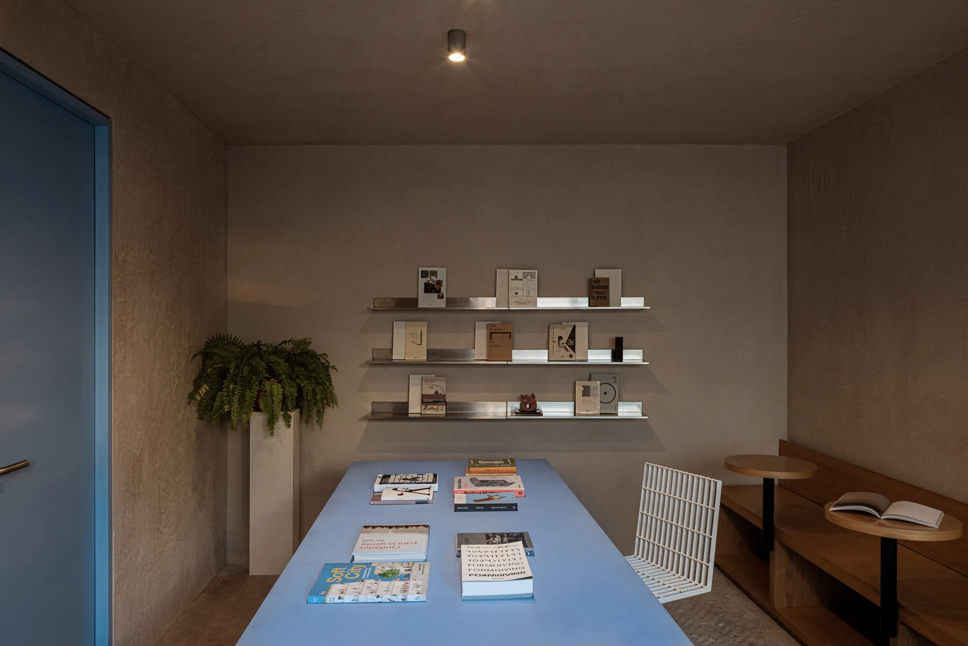 A spacious, modern bookshop featuring minimalist concrete shelving and metal accents.