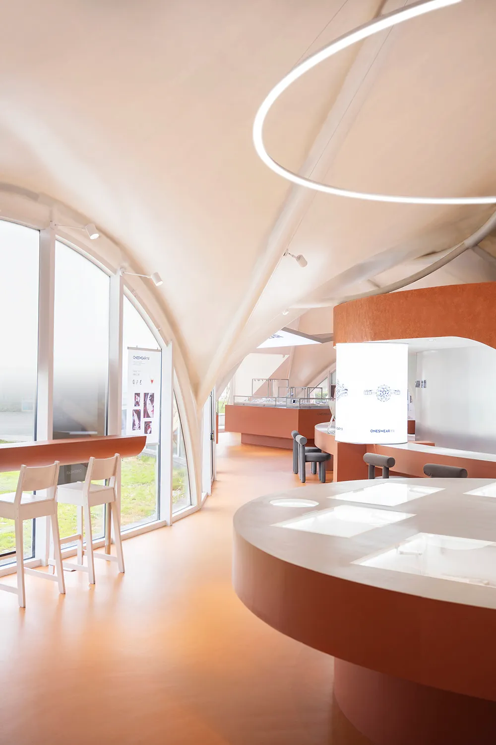 Organic-shaped room with modern furniture, large windows, and a spiral light fixture.