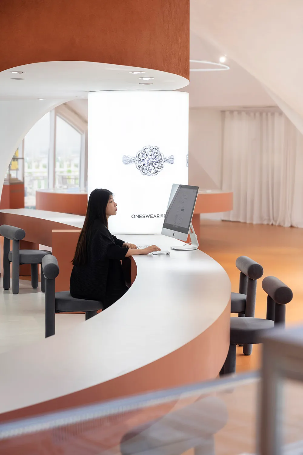 A minimalist retail shop with a white curved reception counter.