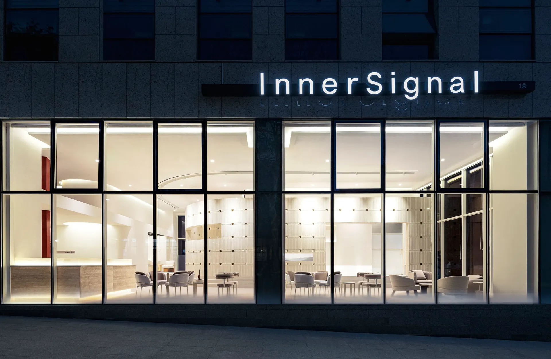 Modern retail storefront with illuminated glass facade at night.