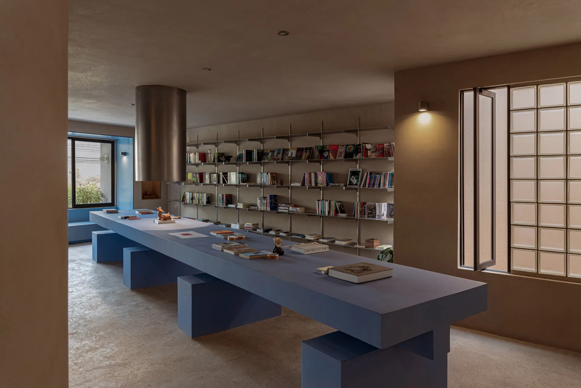 寬敞的工業風圖書館,混凝土地板與牆面,長桌擺放書籍,書架充滿藏書