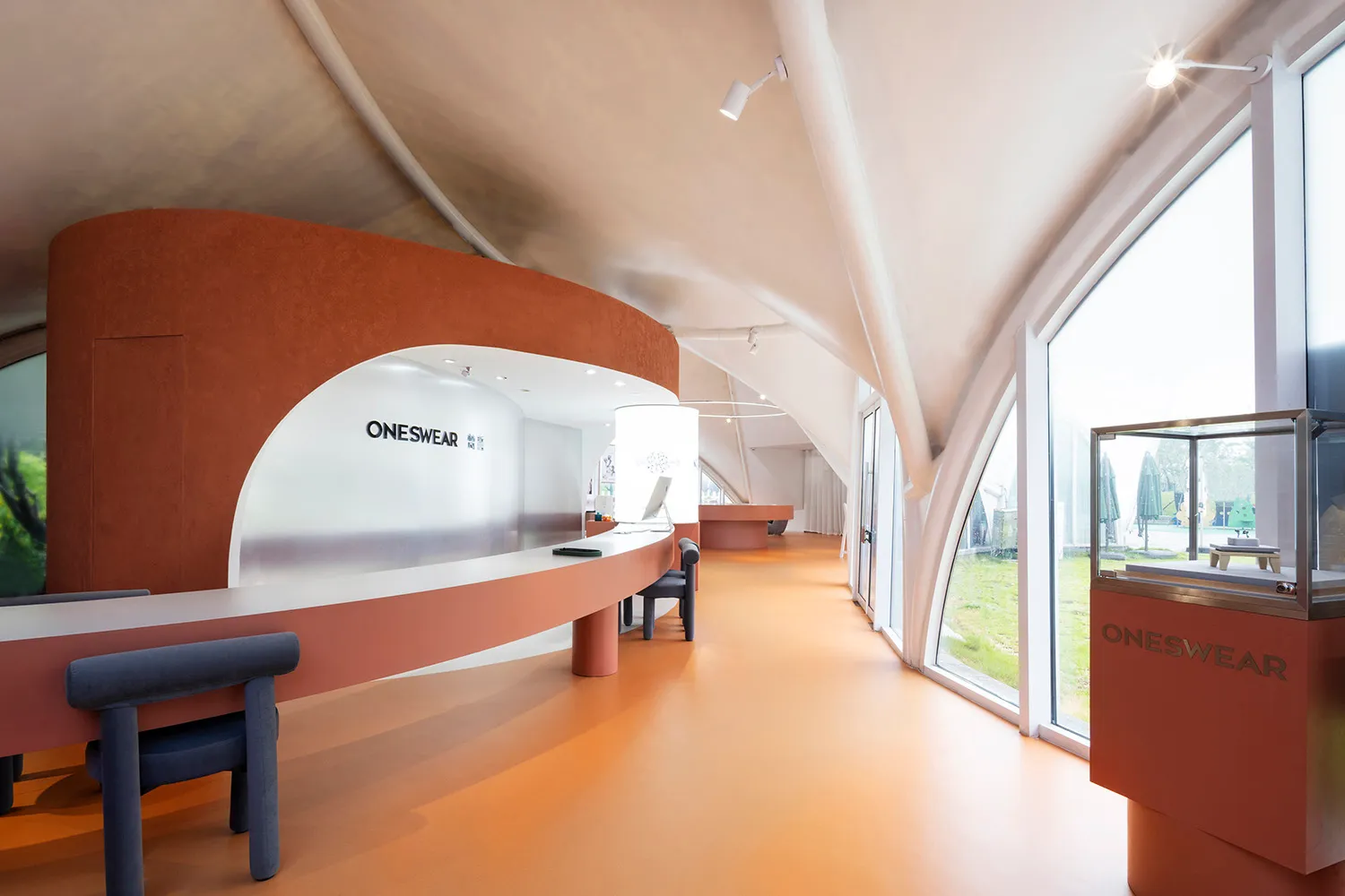 A modern retail showroom featuring curved concrete walls and a spacious interior designed for a contemporary aesthetic.