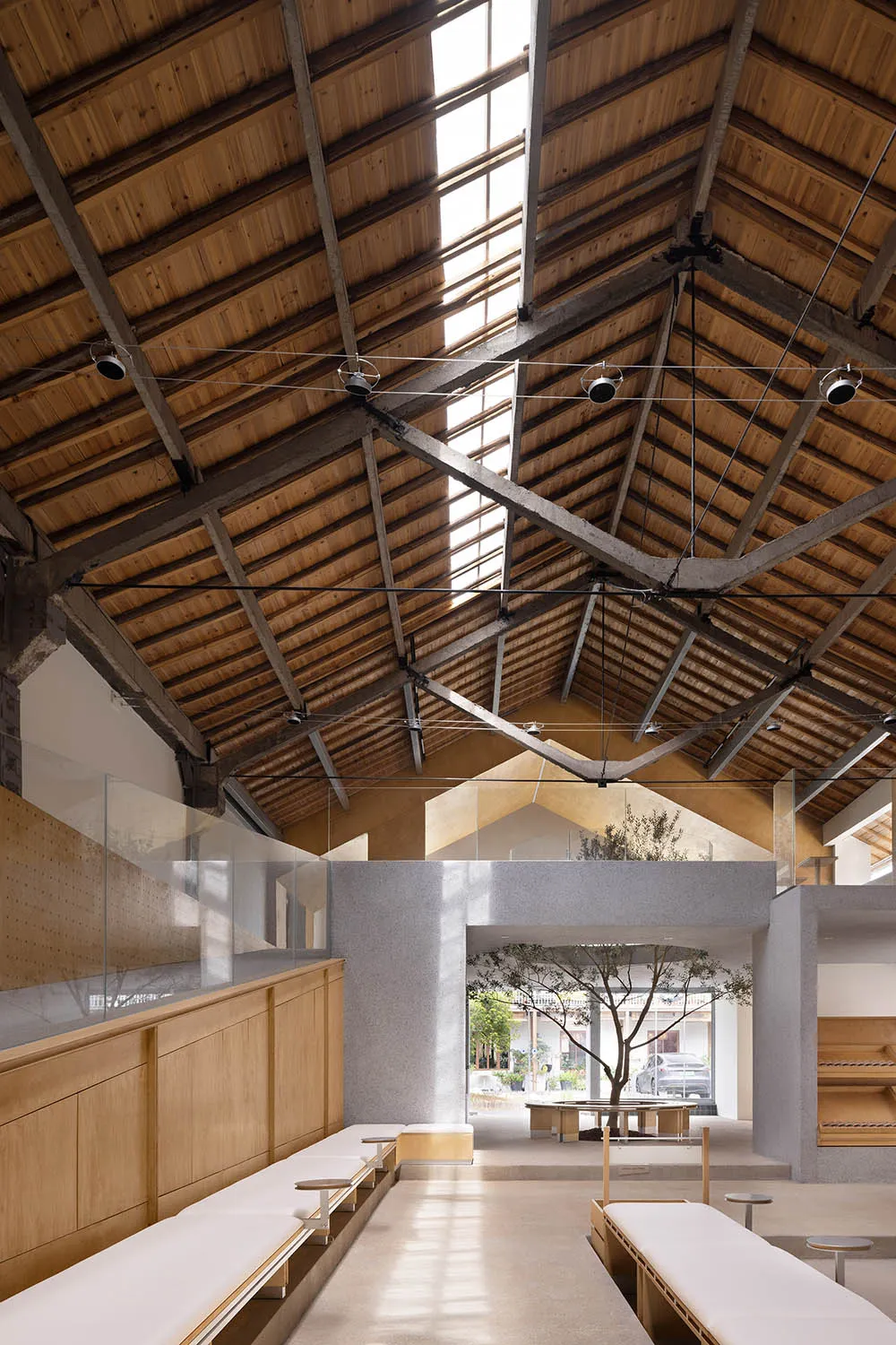 Industrial-style interior with a wooden roof, white benches, and a glass partition.