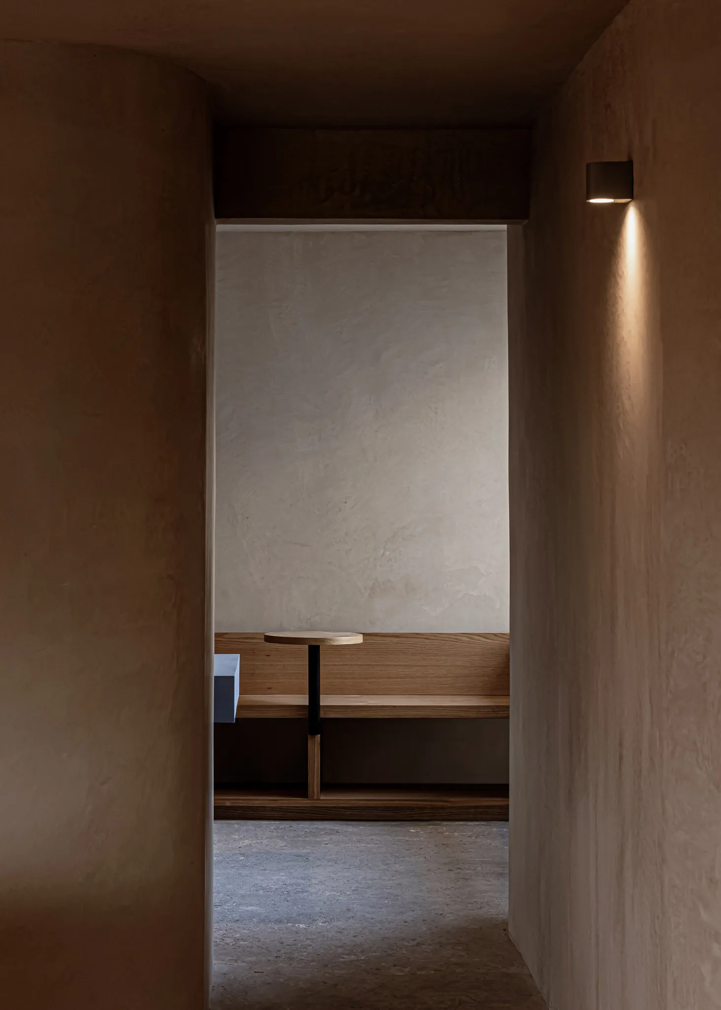 Minimalist room with wooden furniture, concrete walls, and soft lighting, designed to create a serene and modern atmosphere.
